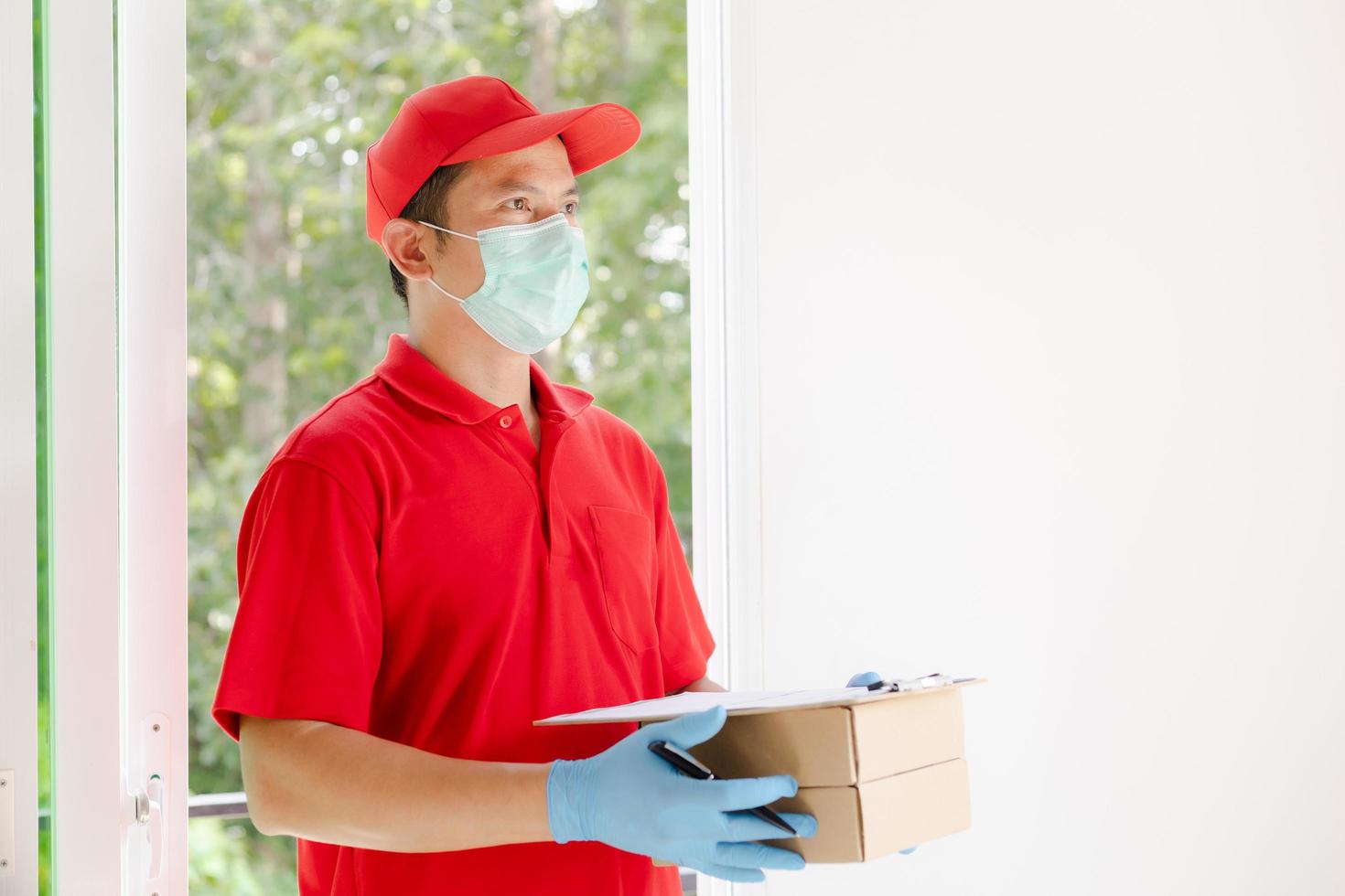 un repartidor con un vestido rojo sostiene una caja de paquetería. foto