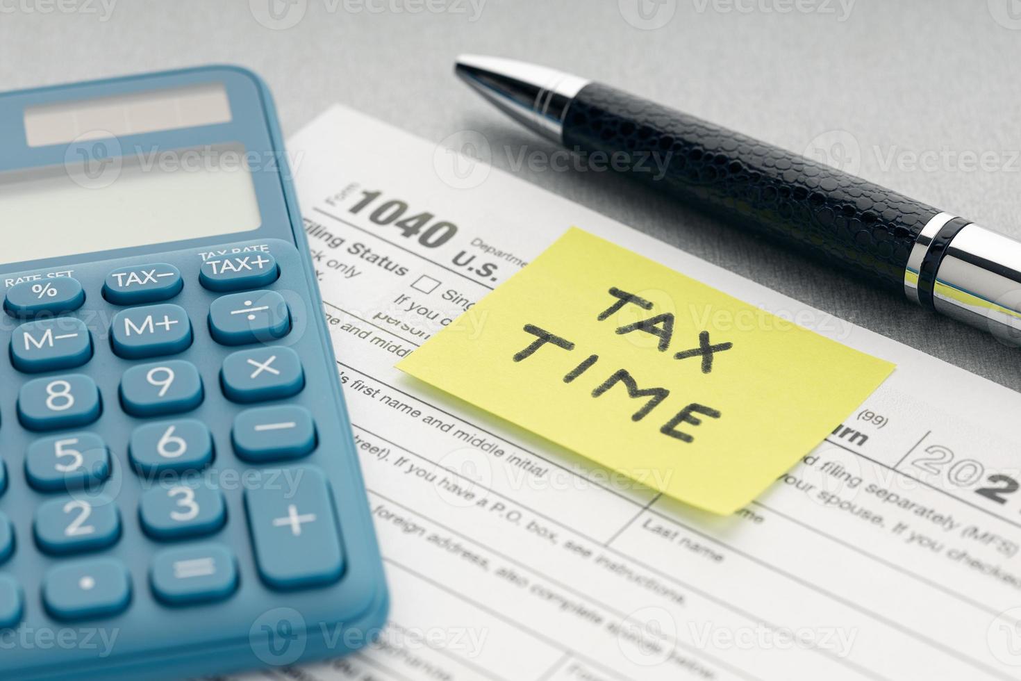 Tax time concept. Yellow note with message, tax form, calculator and pen on table photo