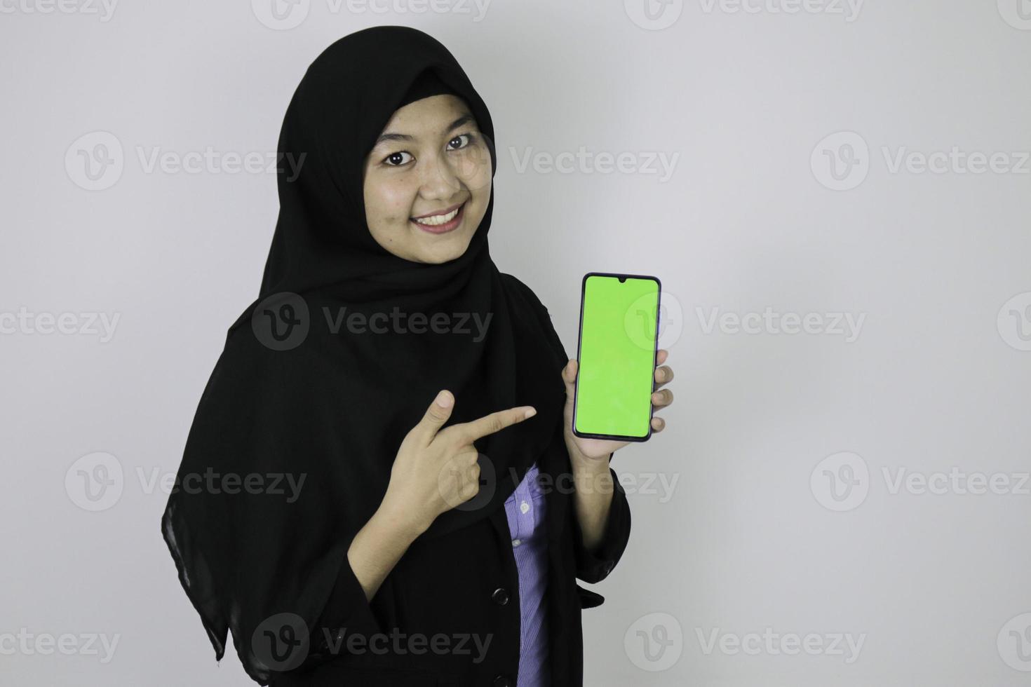 Happy asian islamic business women pointing and show blank screen on phone. photo