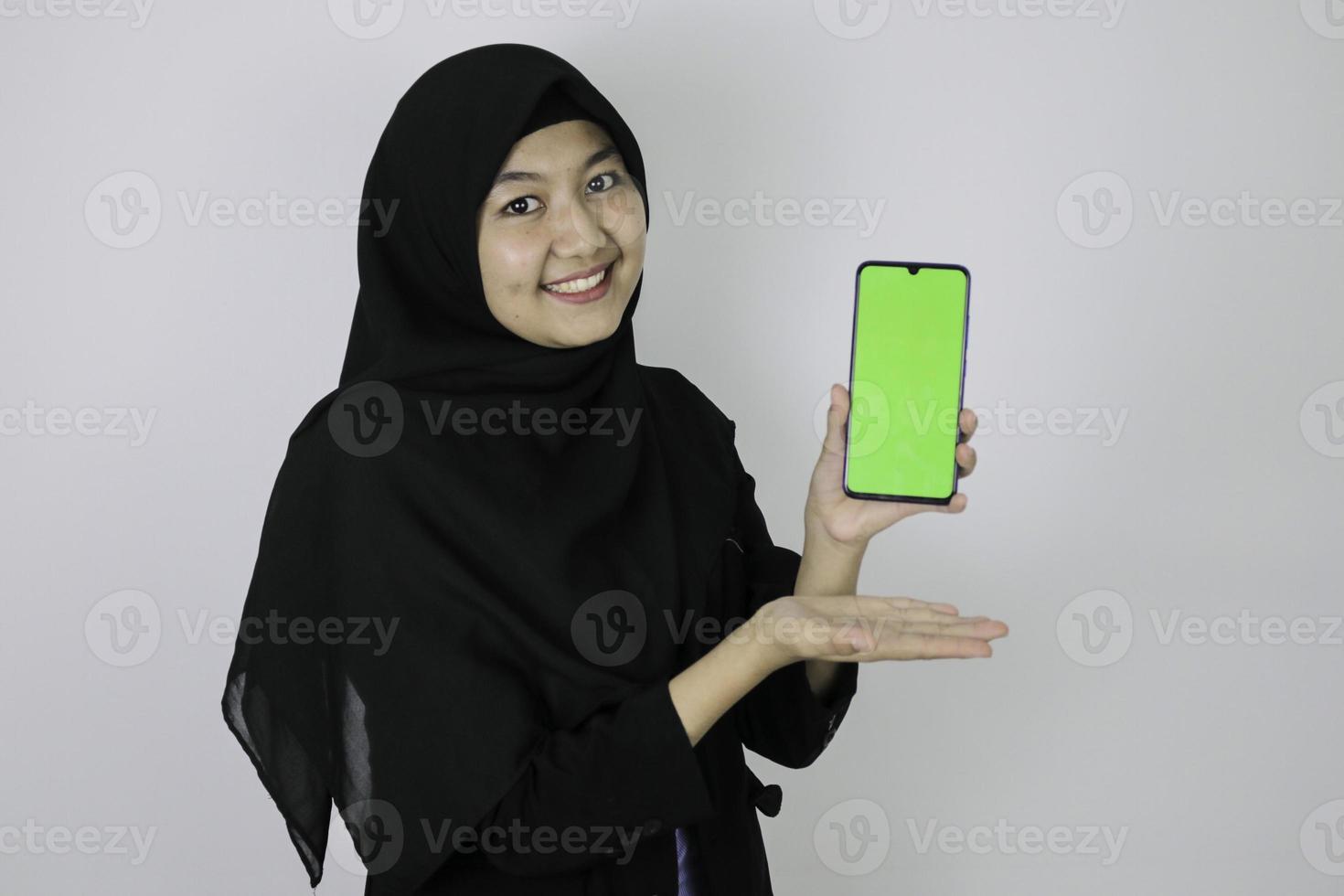 Happy asian islamic business women pointing and show blank screen on phone. photo