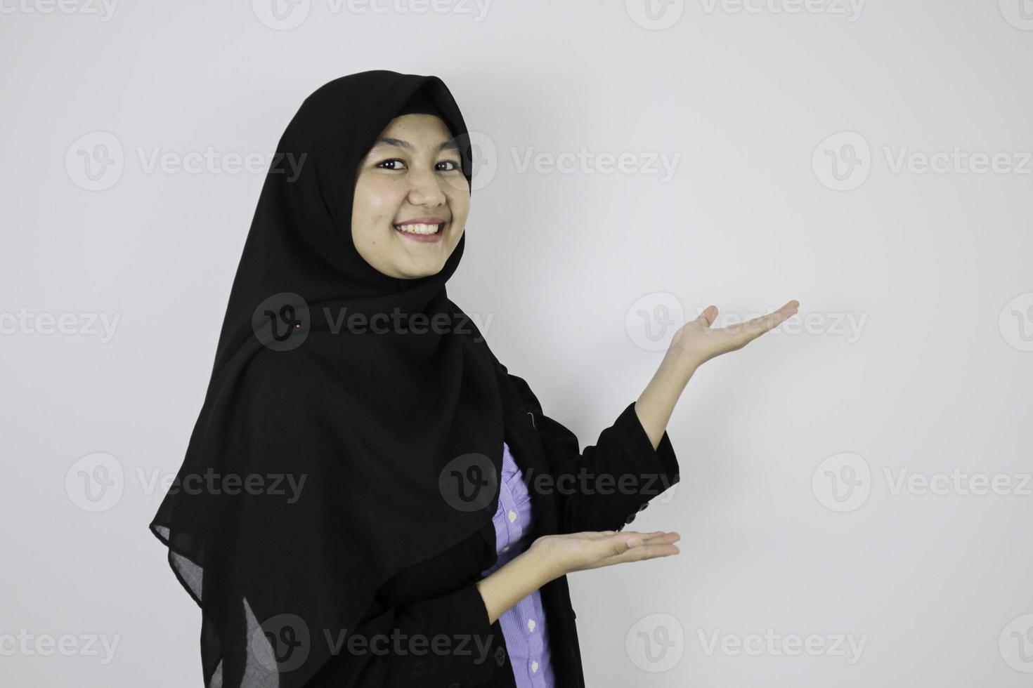 Happy Young Asian Islam woman wearing headscarf is smile and pointing beside. photo