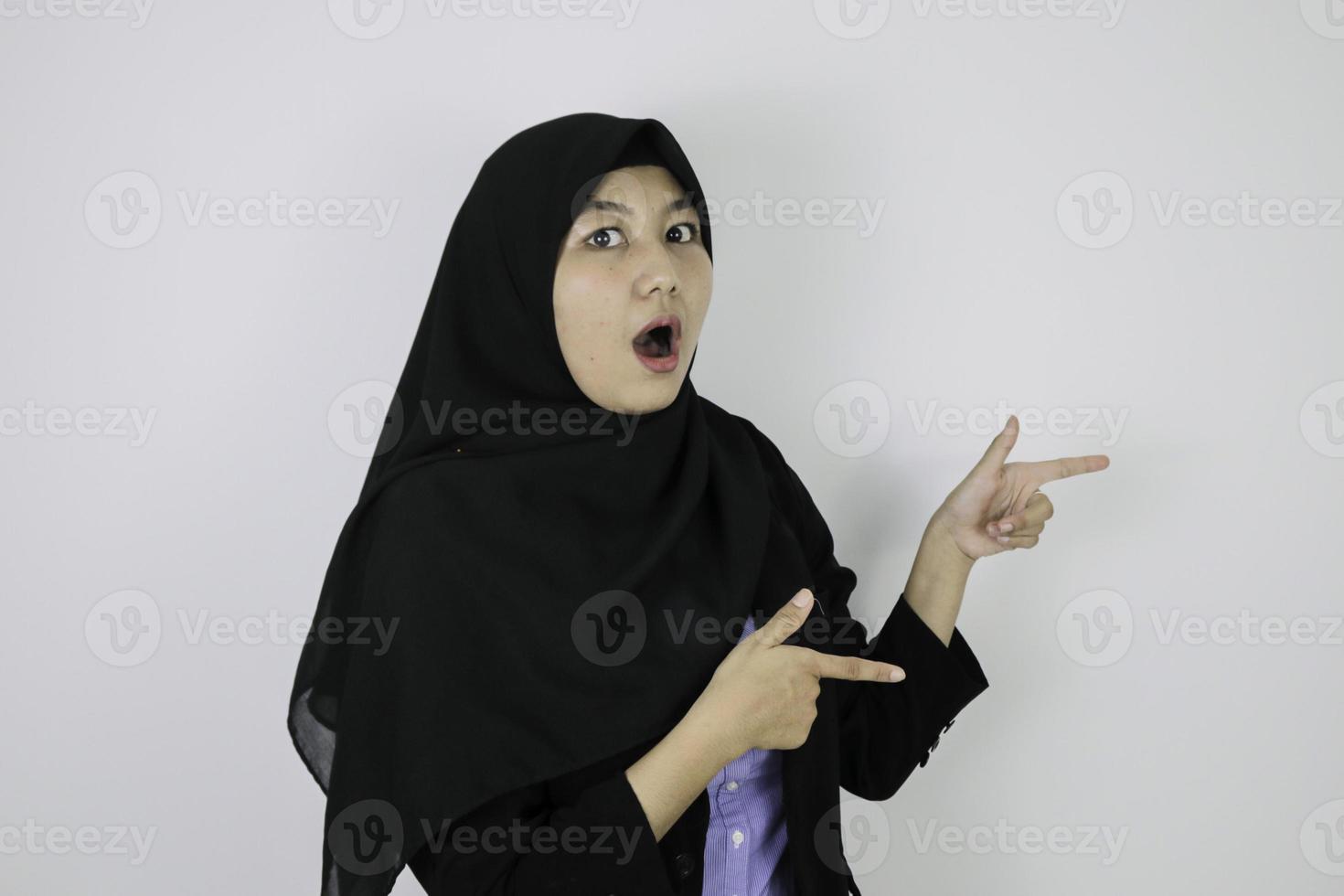 Shock Young Asian Islam woman wearing headscarf is smile and pointing beside. photo