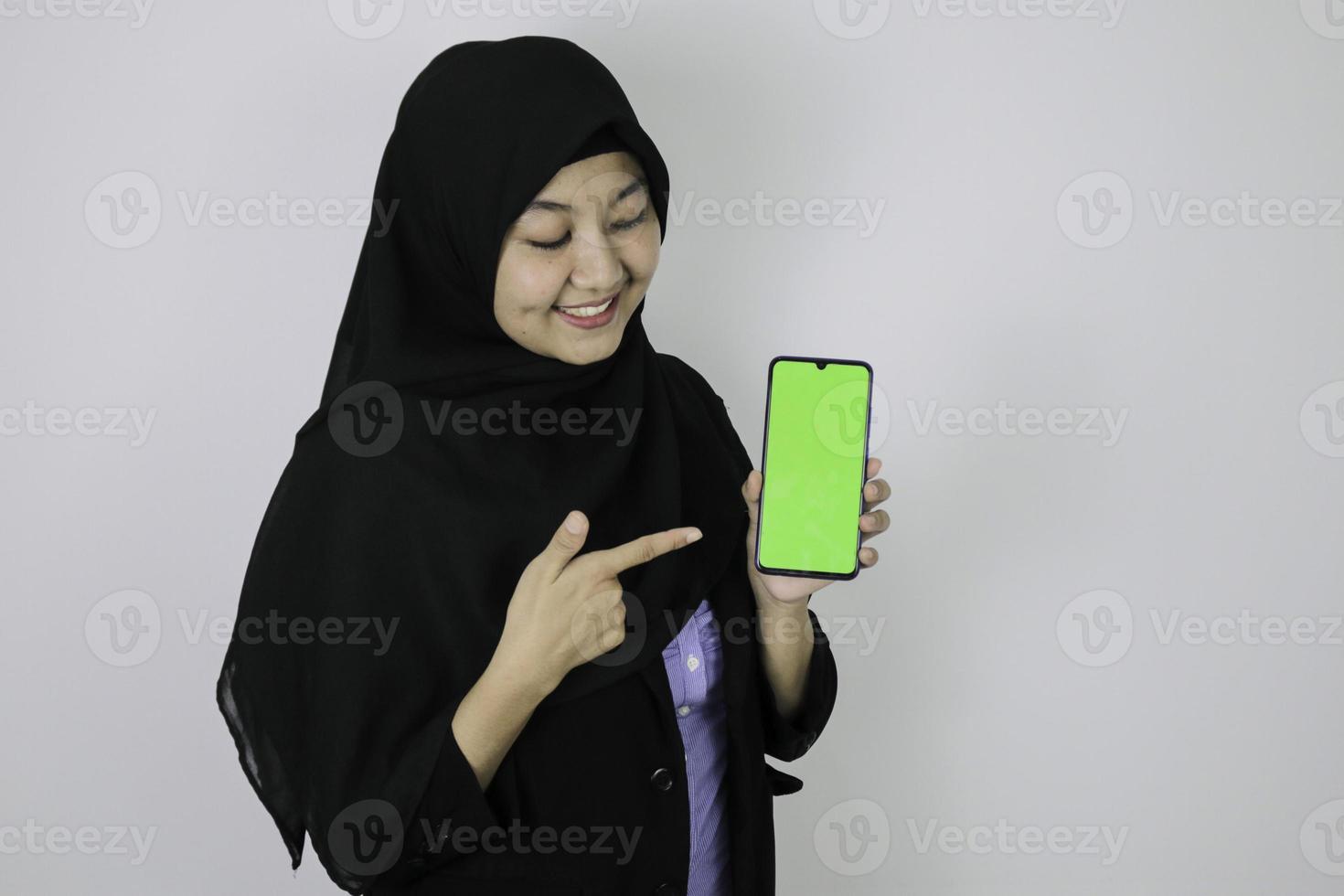 Happy asian islamic business women pointing and show blank screen on phone. photo