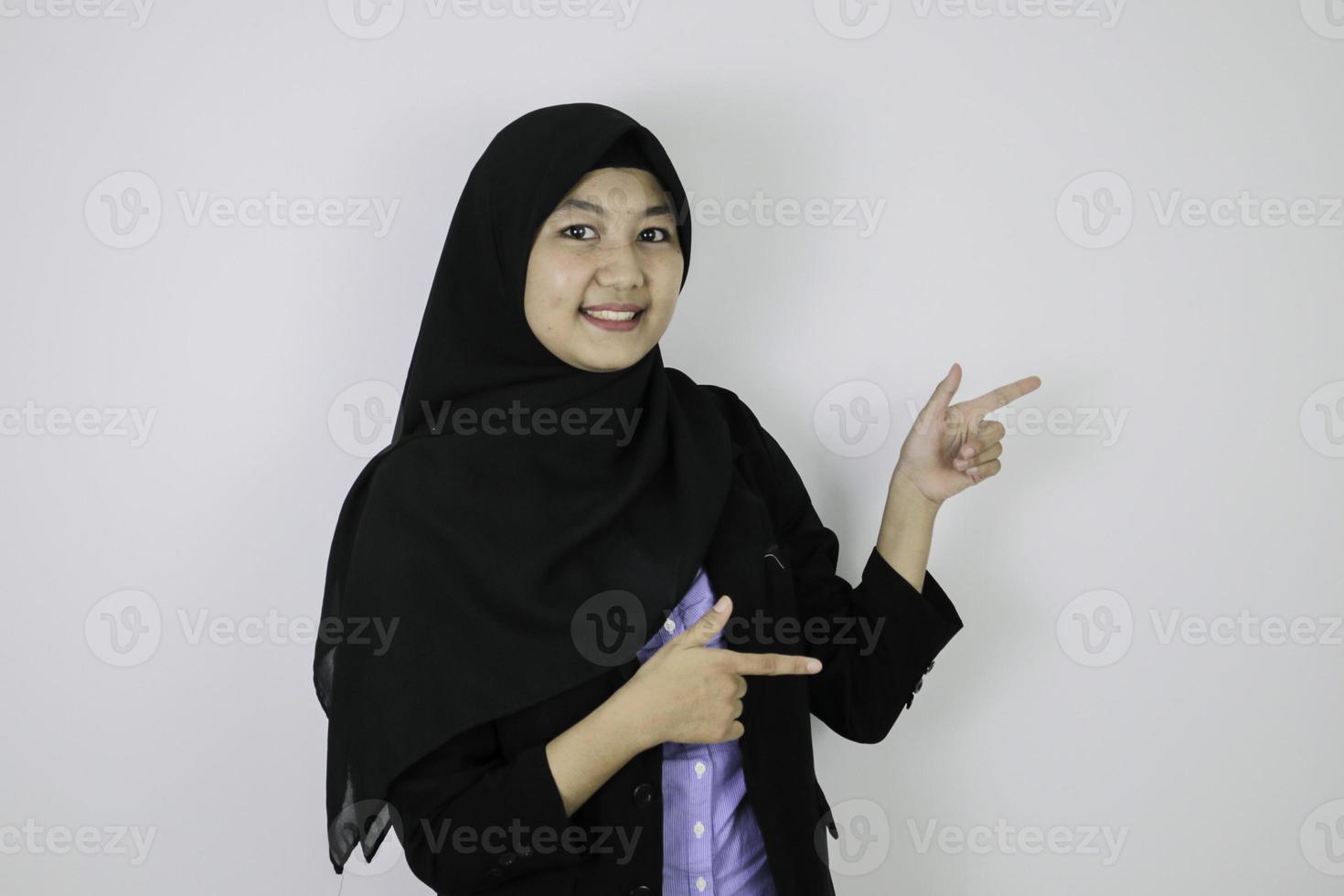 Happy Young Asian Islam woman wearing headscarf is smile and pointing beside. photo