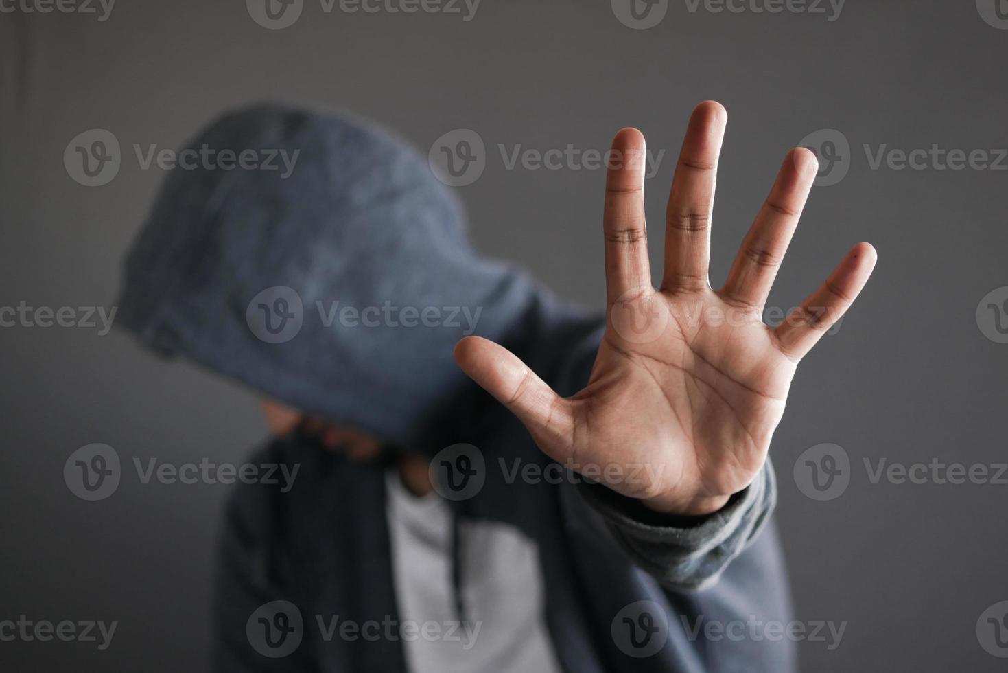 sad man in hood cover face with hands isolated in black. photo