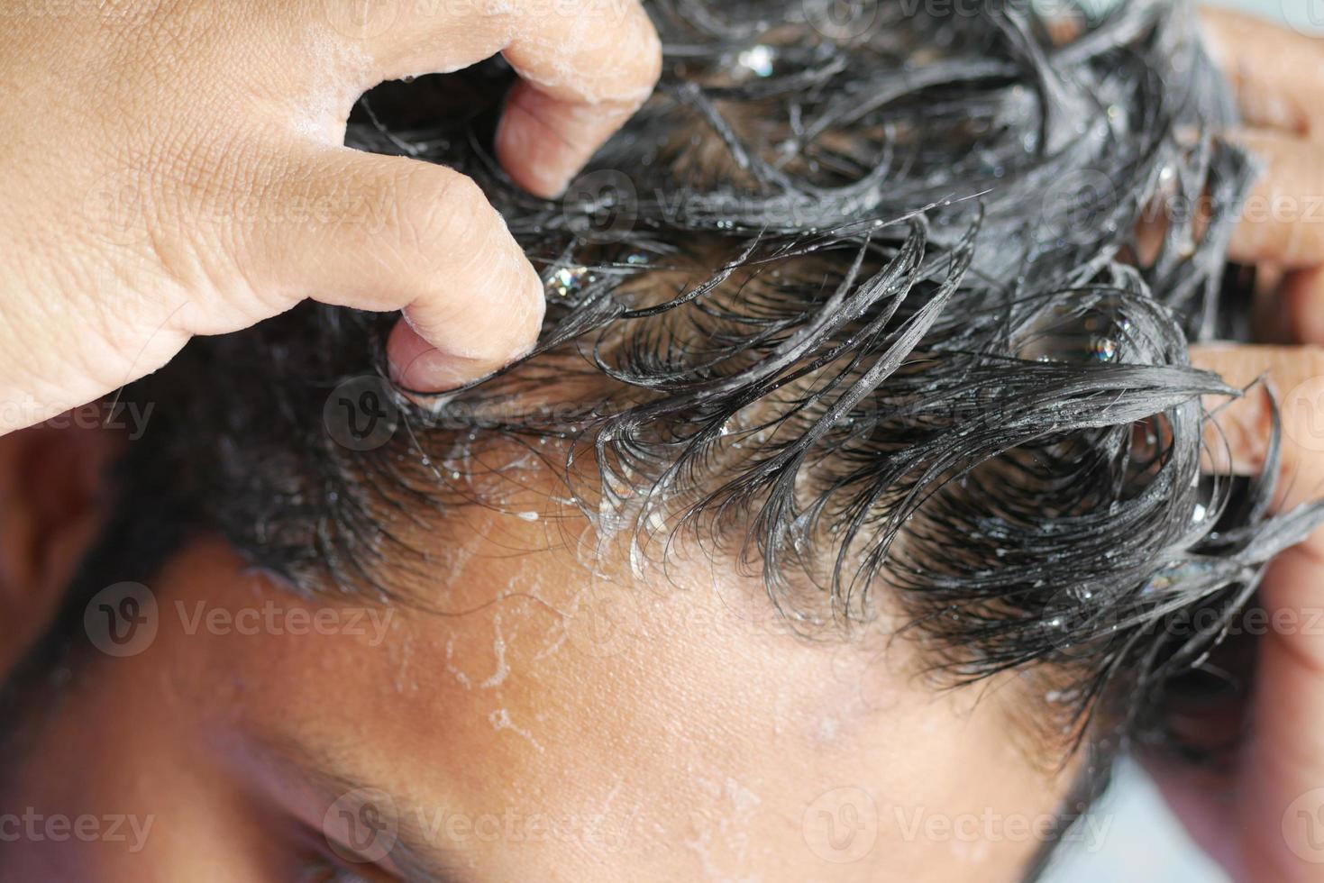 young men washes h his hair with shampoo . photo