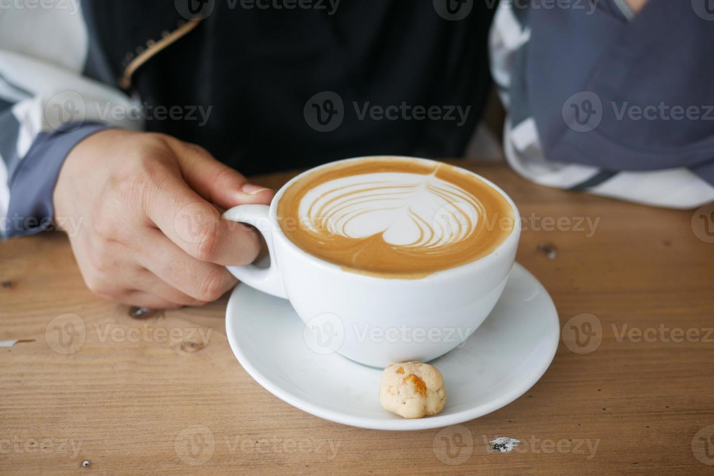 top view of a cup of late coffee with heart shape design on top on cafe table photo