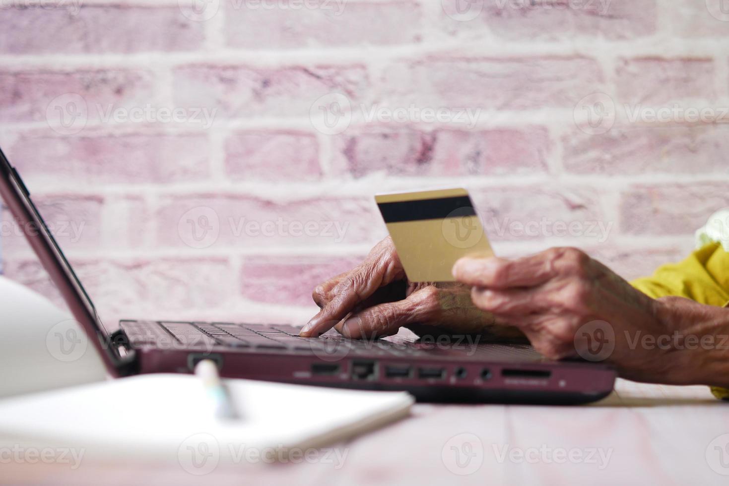 senior women hand holding credit card and using laptop for making payment photo