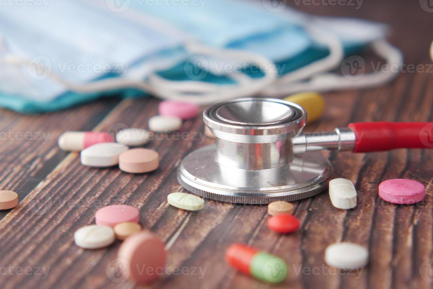 stethoscope and pills container on wooden background photo