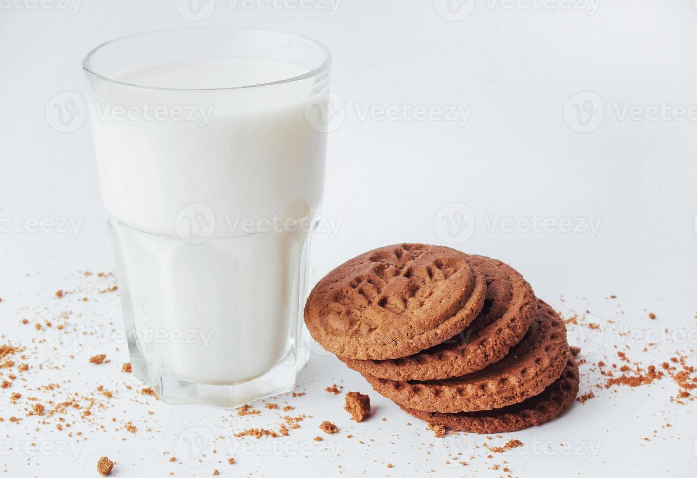vaso transparente de leche y galletas en un fondo blanco foto