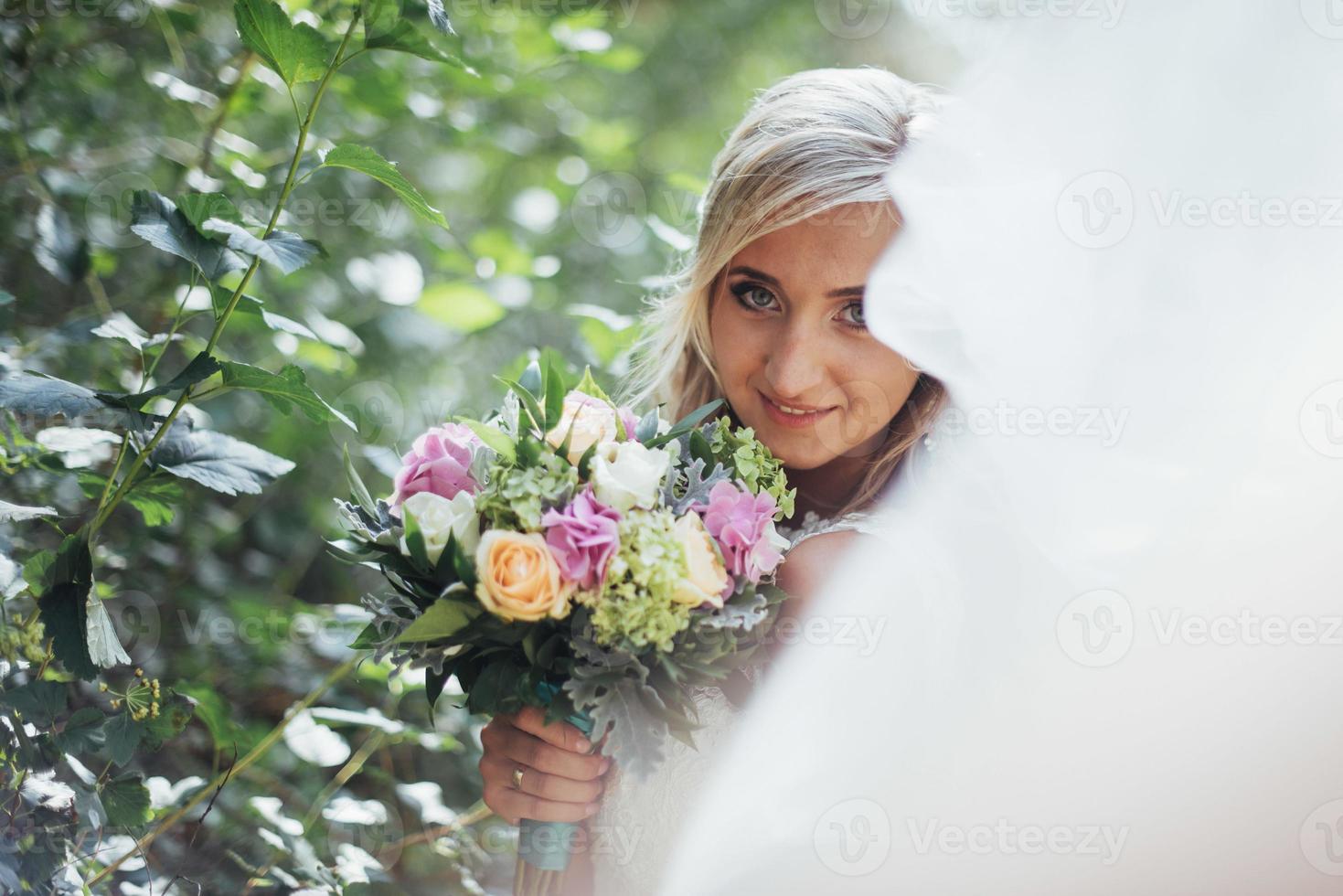 Portrait of a happy bride posing with veil photo