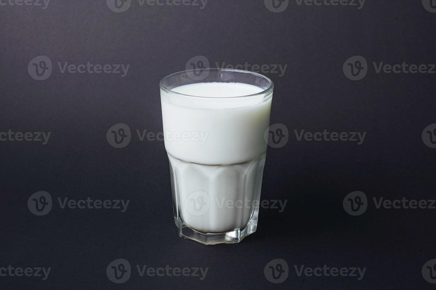 Transparent glass of milk on a black photo