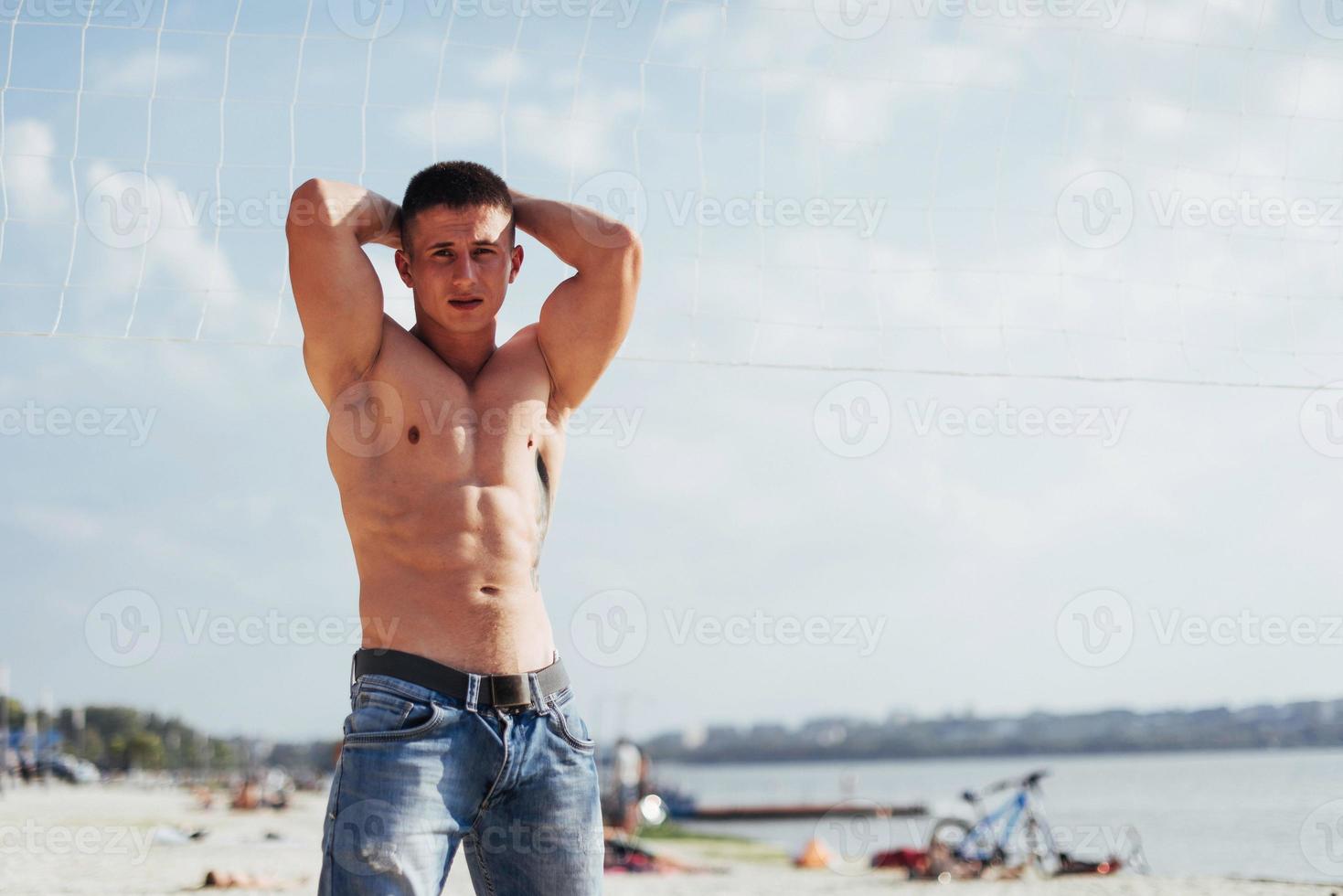 muscular male model with perfect body posing in blue jeans photo