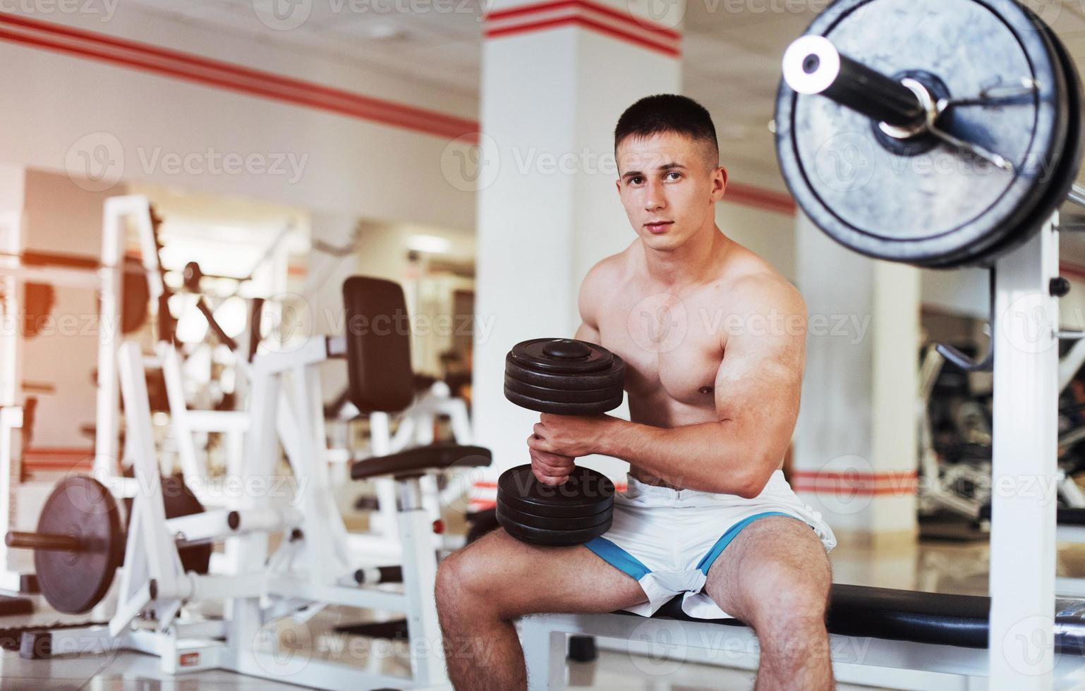 Portrait of a beautiful athletic guy muscles with weights photo