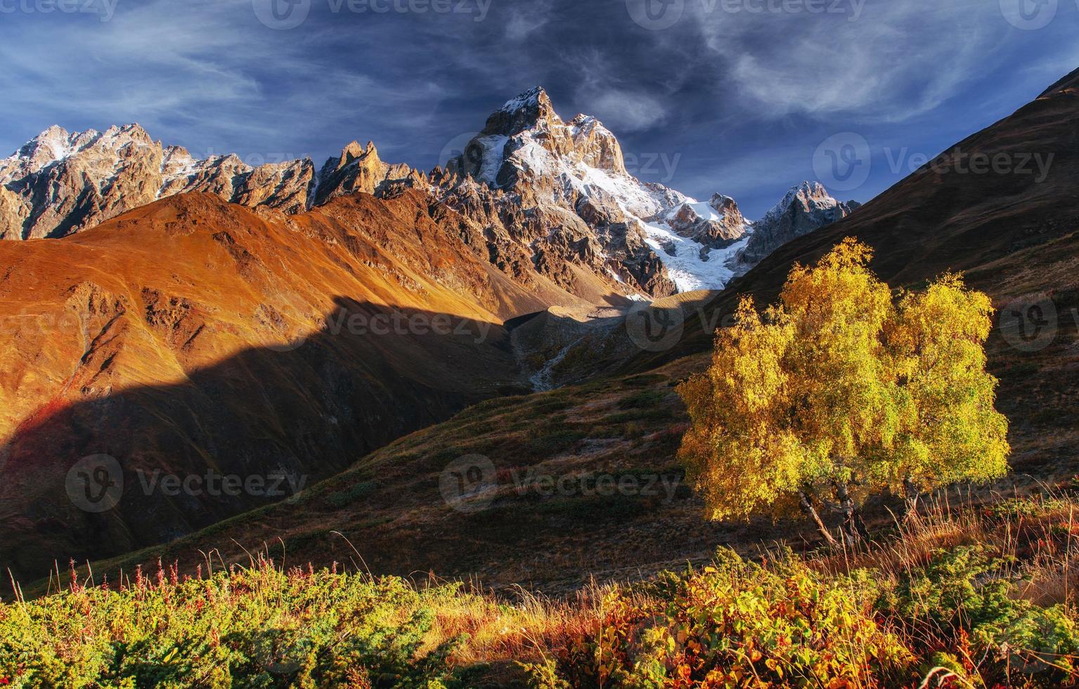 Autumn landscape and snowy peaks in the sun photo