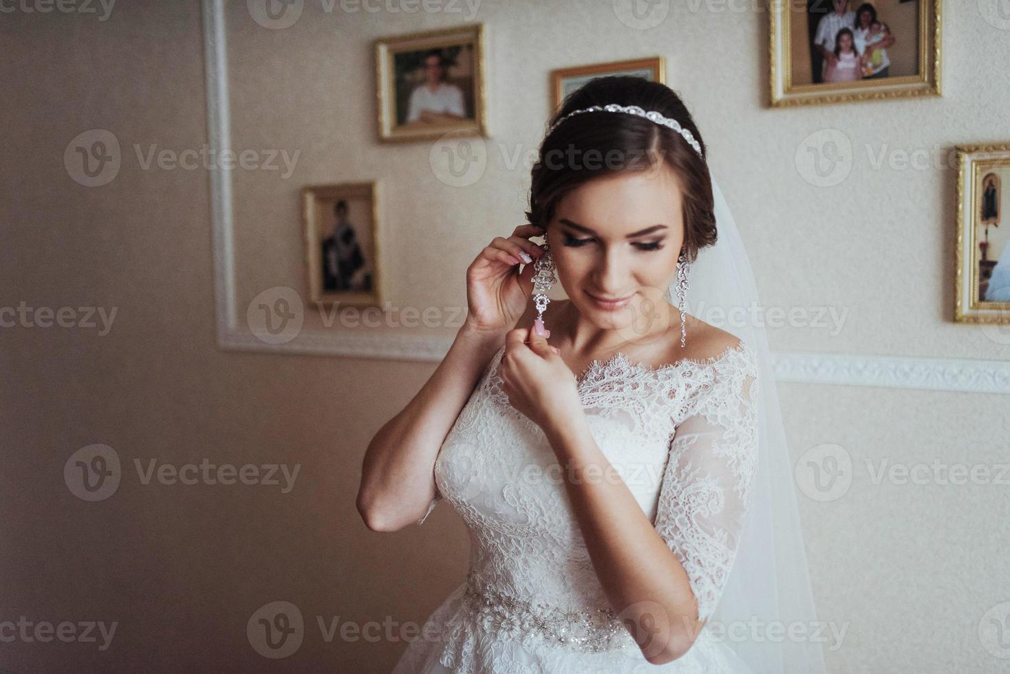 Wedding day. Beautiful bride trying on earrings photo