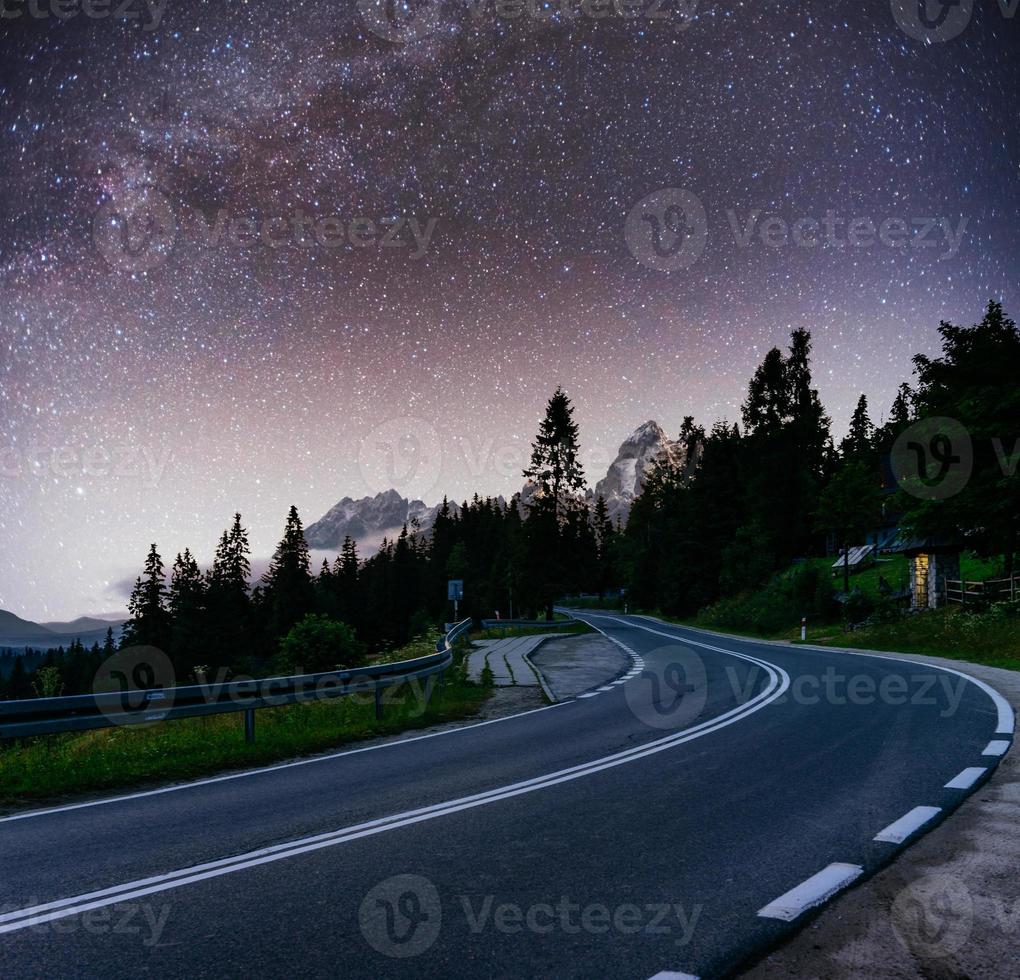 cielo estrellado sobre las montañas. la carretera asfaltada foto
