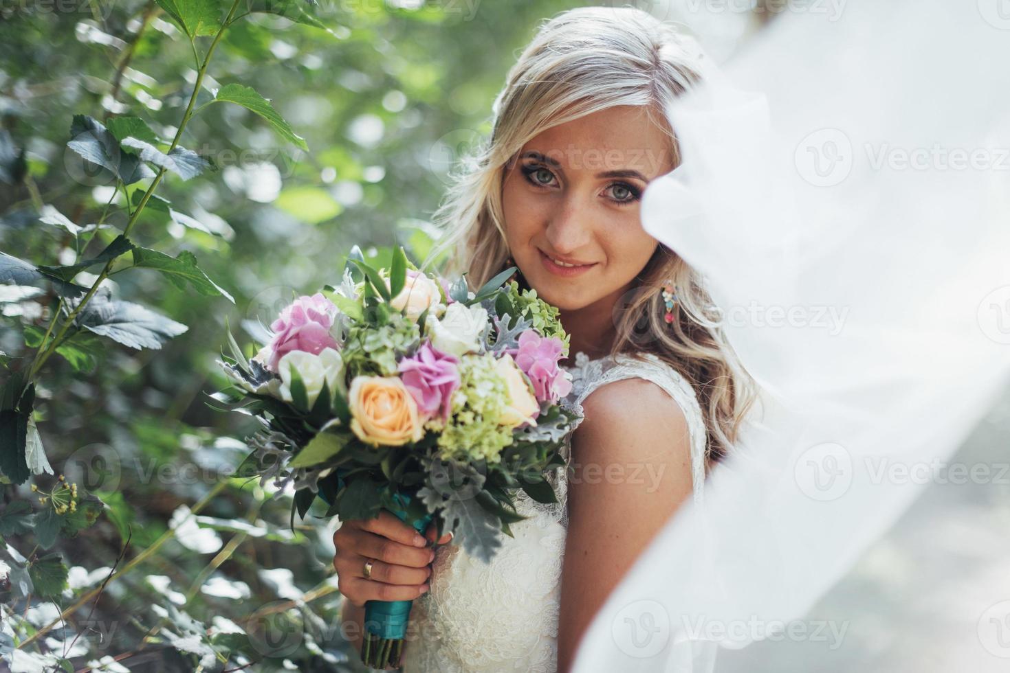 Portrait of a happy bride posing with veil photo