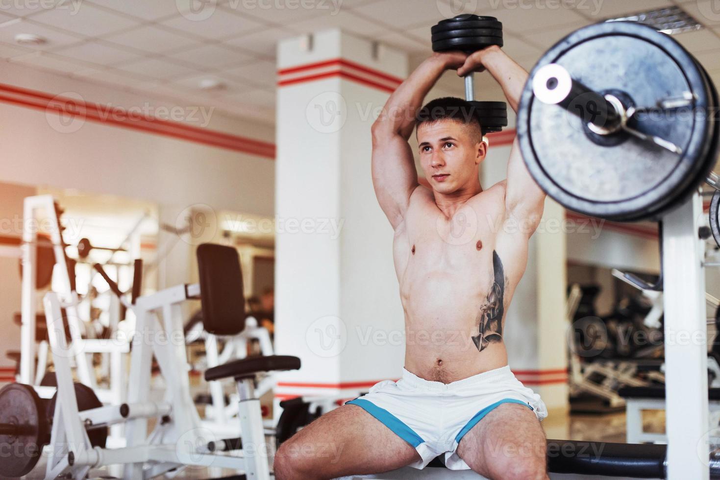 retrato de un hermoso chico atlético músculos con pesas foto