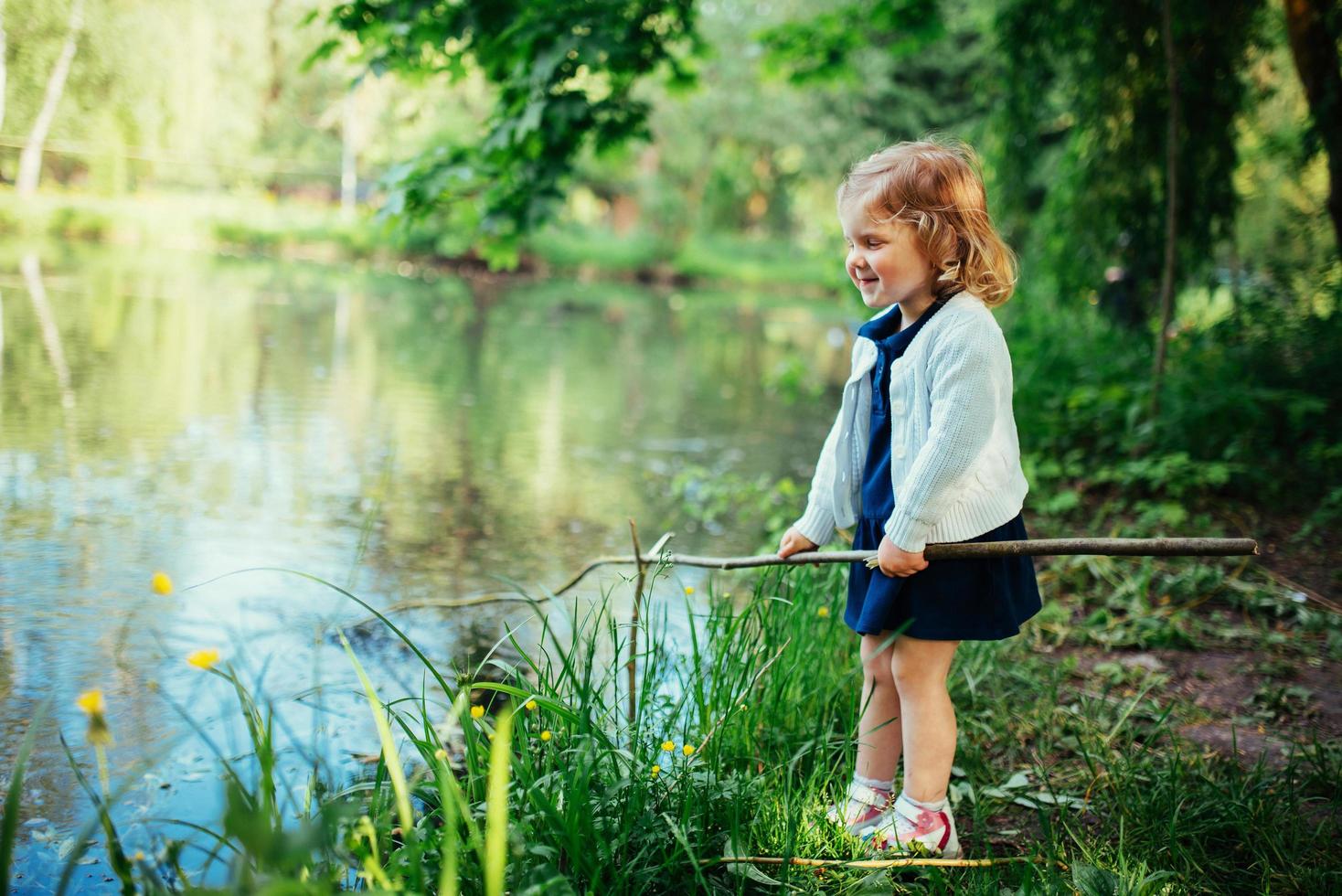 Cute little blonde girl is against the background of water and g photo