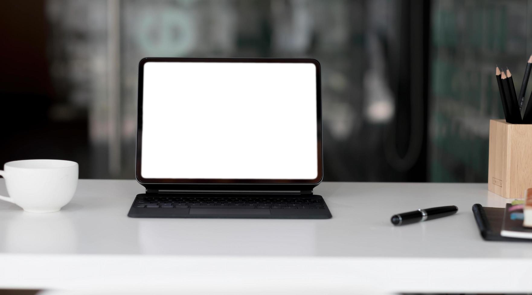 Side view of contemporary workplace with laptop computer, notebook, coffee cup and stationery on wooden table. photo