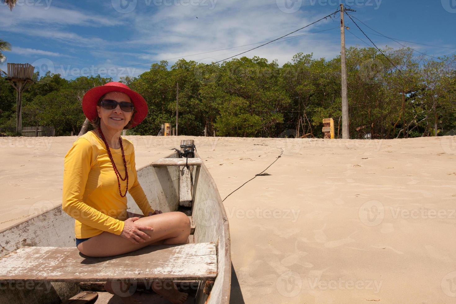 Lady sitting in an old wooden fishing boat enjoying herself at the beach in Corumbau, Bahia, Brazil photo