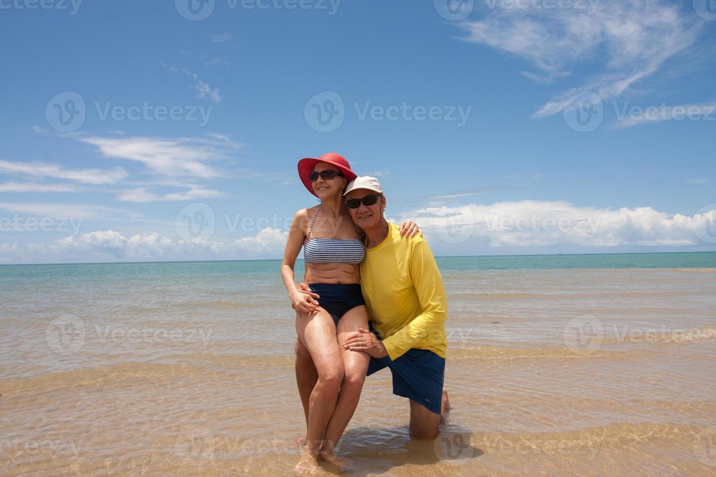 Couple having fun at the beach kneeling on a sandbar in Ponta do Corumbau, Bahia, Brazil photo