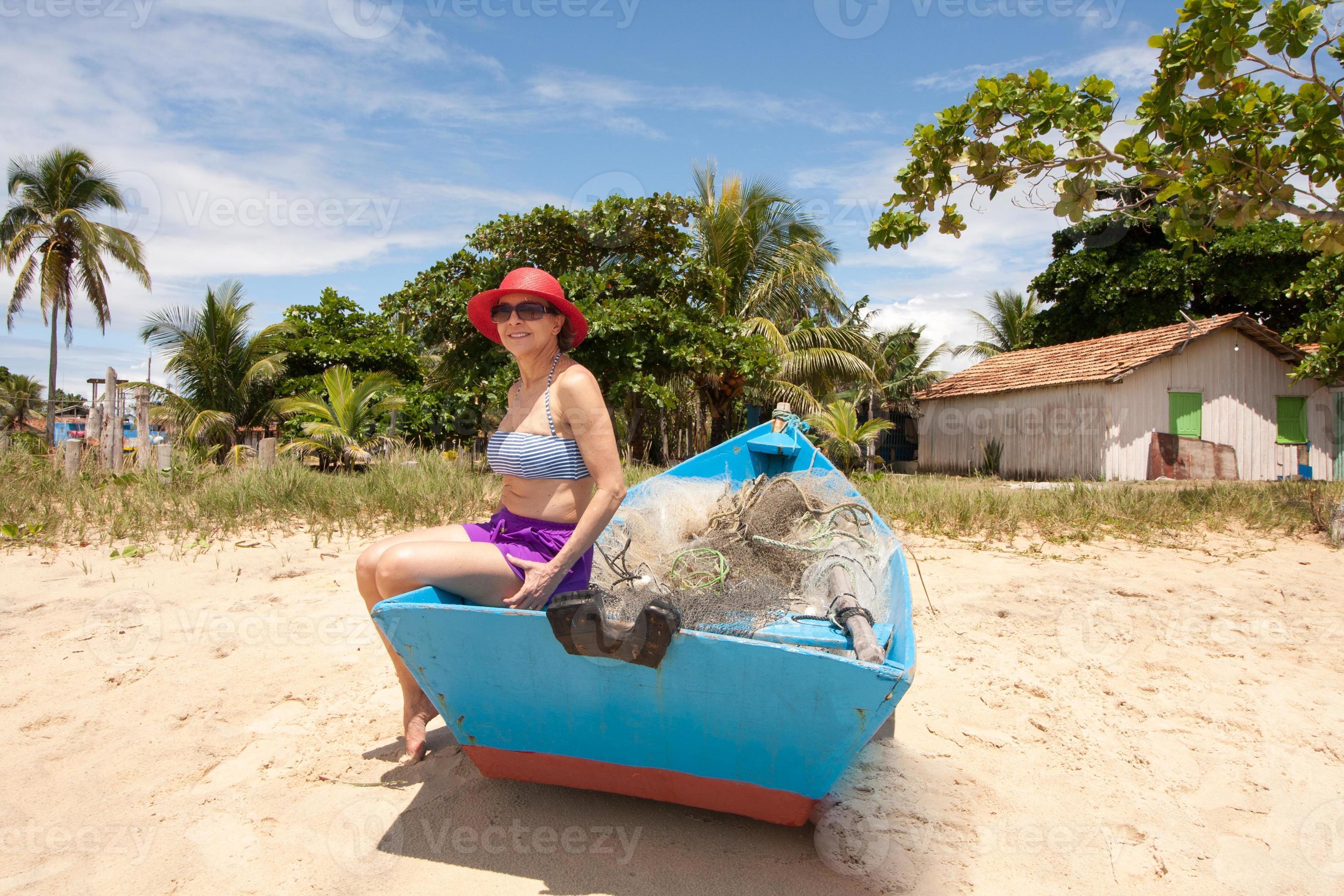 Lady sitting in an old wooden fishing boat enjoying herself at the beach in  Corumbau, Bahia, Brazil 6572566 Stock Photo at Vecteezy