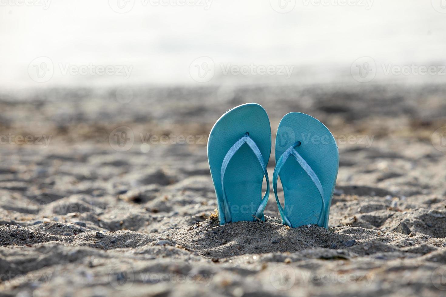 Chanclas en la arena de la playa con foco en primer plano foto