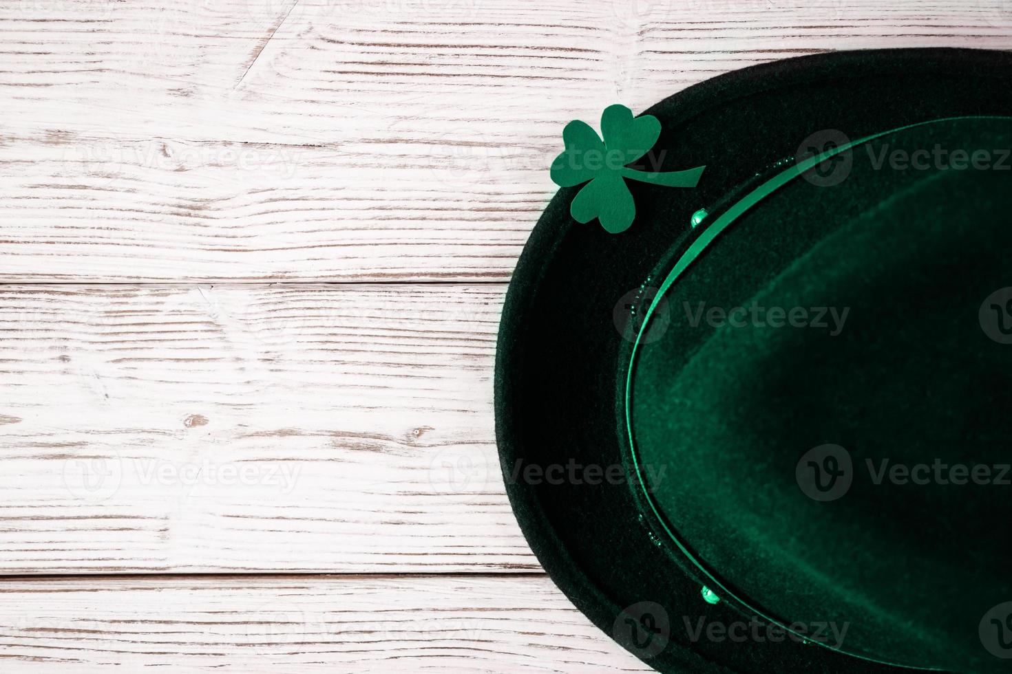 Happy St. Patrick's Day. Leprechaun hat and clover shamrock on a light wooden background. photo