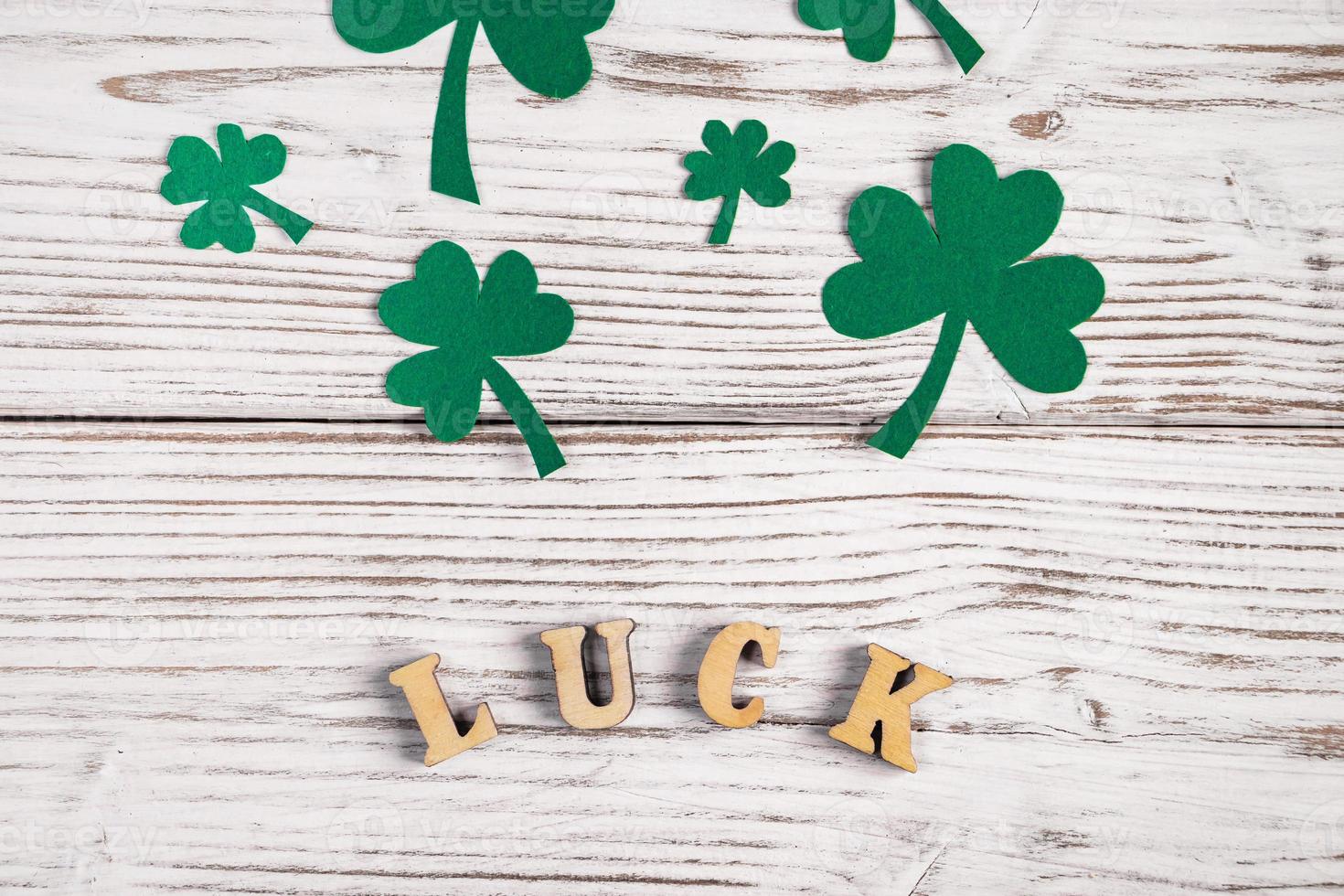 Word luck and shamrock clover leaves on a white wooden background. Happy St. Patrick's Day. photo