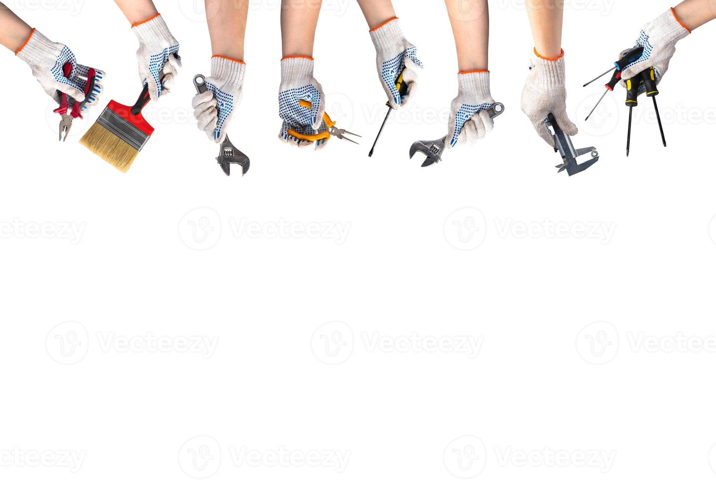 Happy labor day concept. Hands in work gloves hold tools for repair and construction. Wrench, screwdriver, paintbrush, pliers on white background. photo