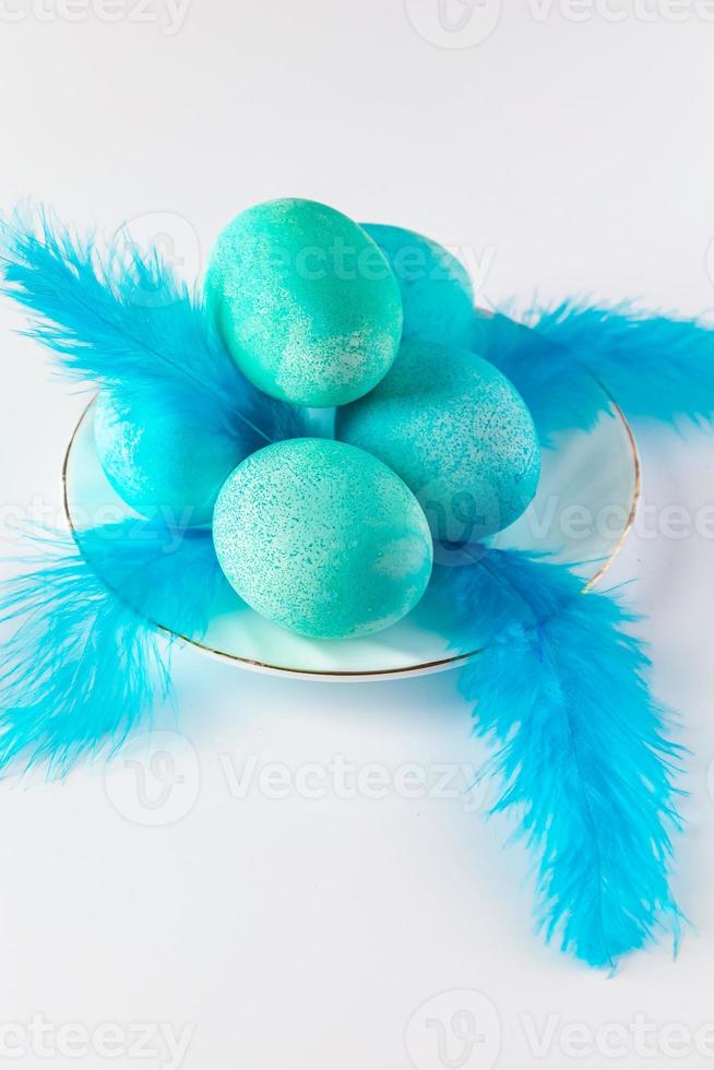 composición de huevos de pascua azules y plumas sobre un fondo claro. foto