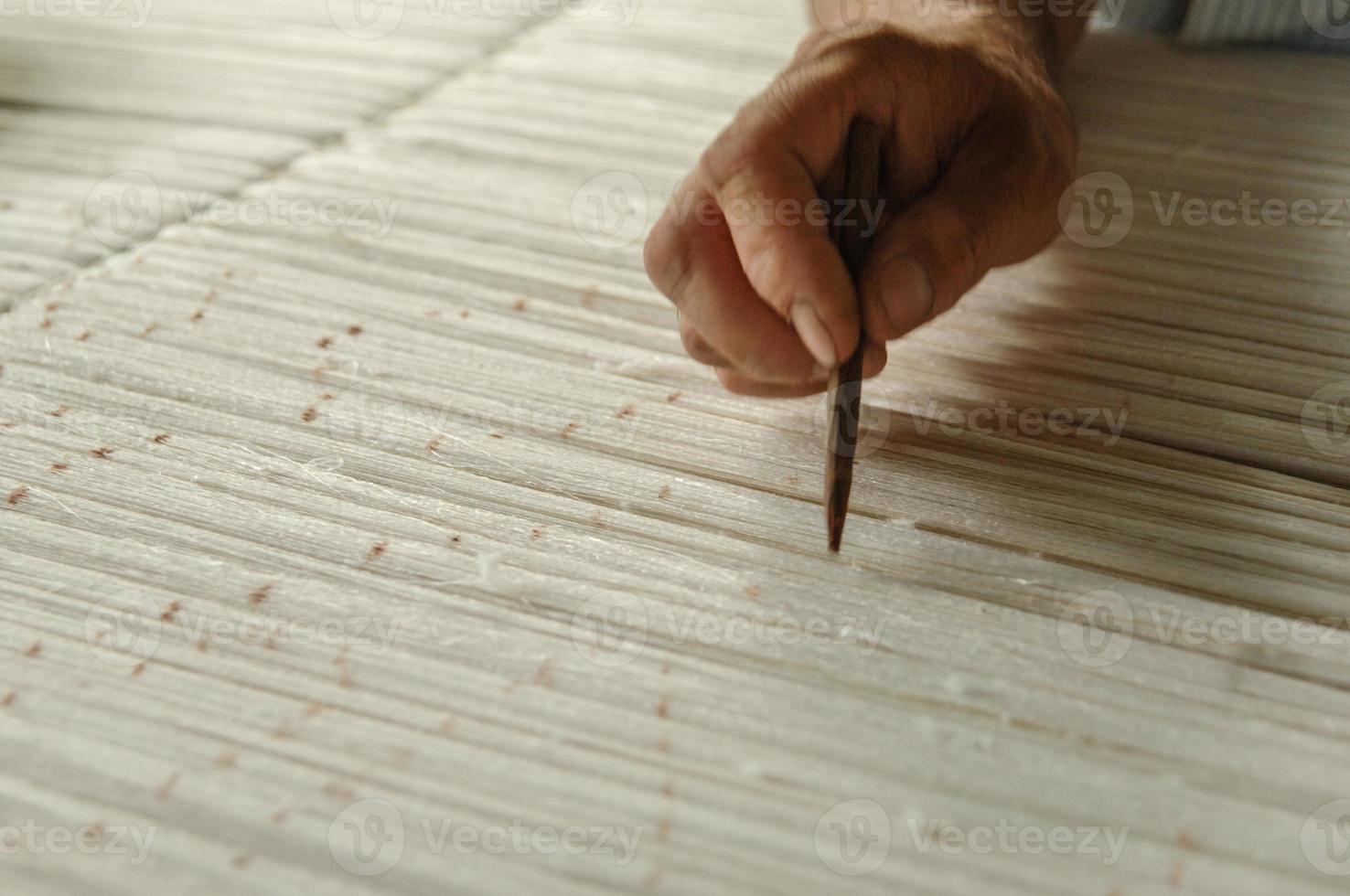 hand with a pencil makes marks on the carpet. weaving and manufacturing of handmade carpets closeup photo