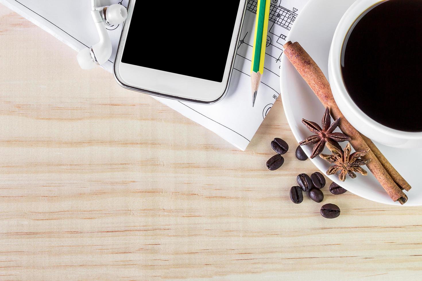 Cup of coffee and smart phone with coffee beans on wooden table background. photo