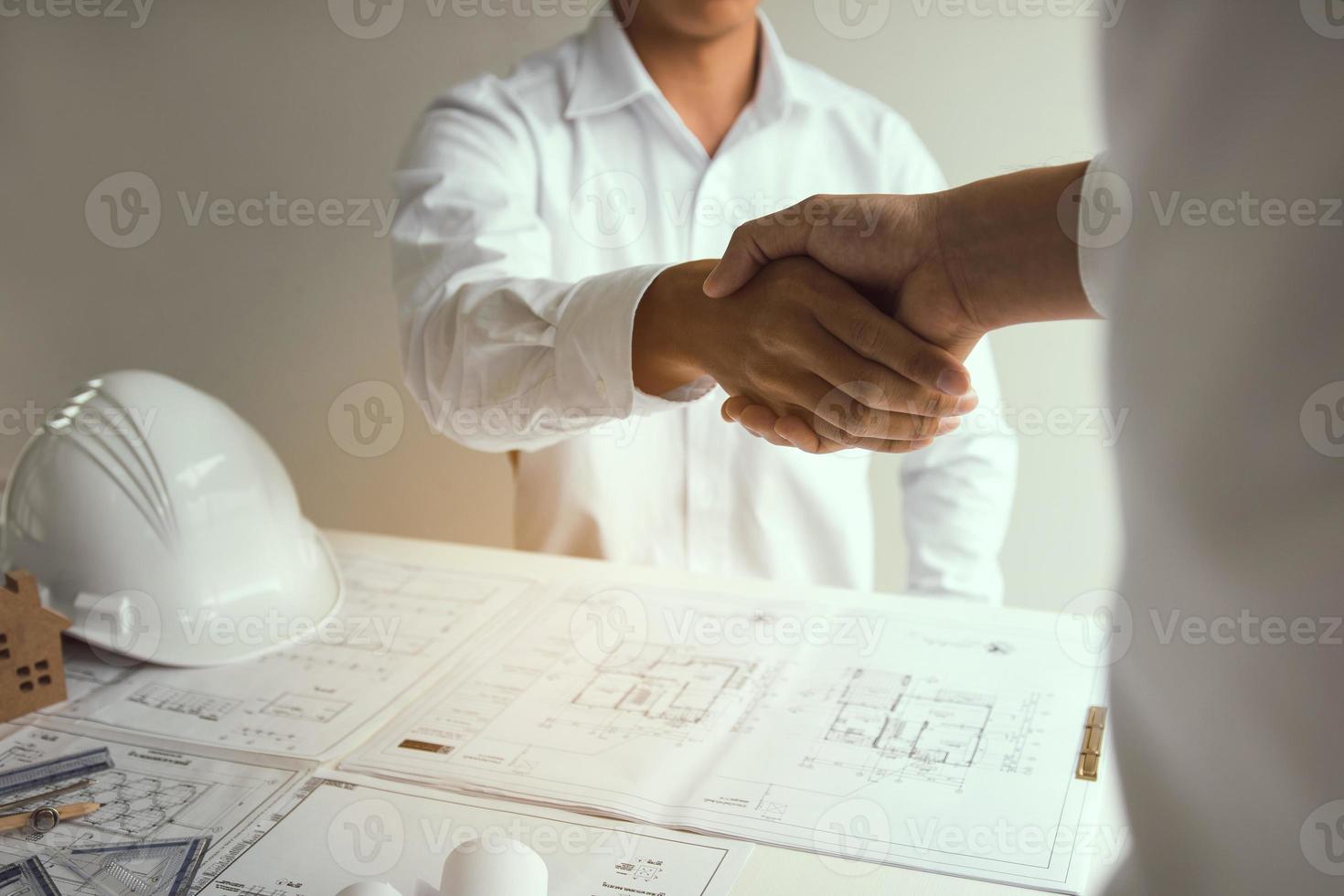 Two partnership engineering man with construction worker greeting shaking hand a foreman at renovating apartment. photo