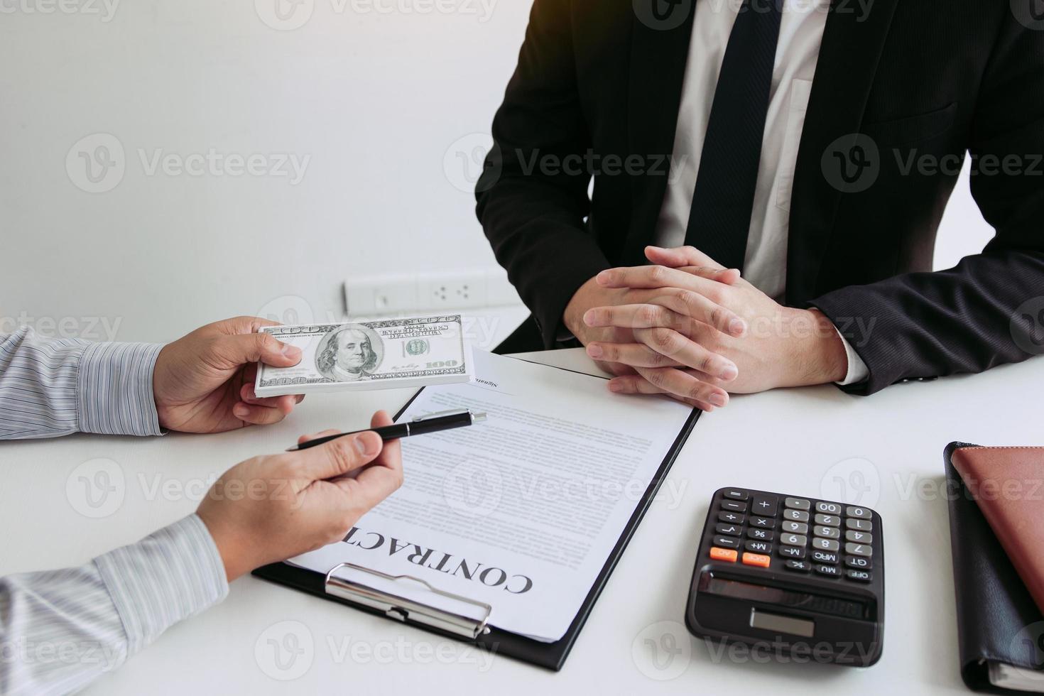 Money in the hands of businessmen who are submitting to entrepreneurs to force the signing of contract documents about corruption concept. photo