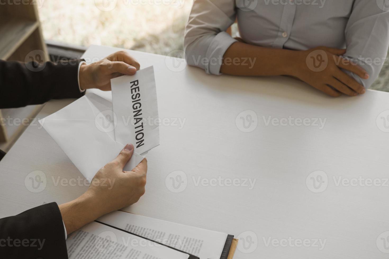 Woman employee takes the handle to the resignation envelope while being handed over to the female manager. photo