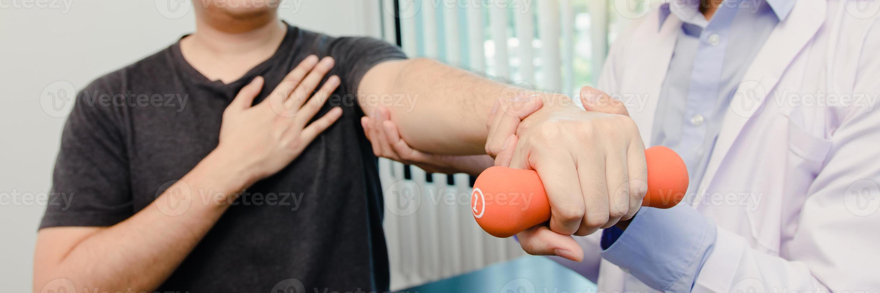 Asian physiotherapists help raise arms for patients to raise dumbbells through his rehabilitation in the clinic. photo