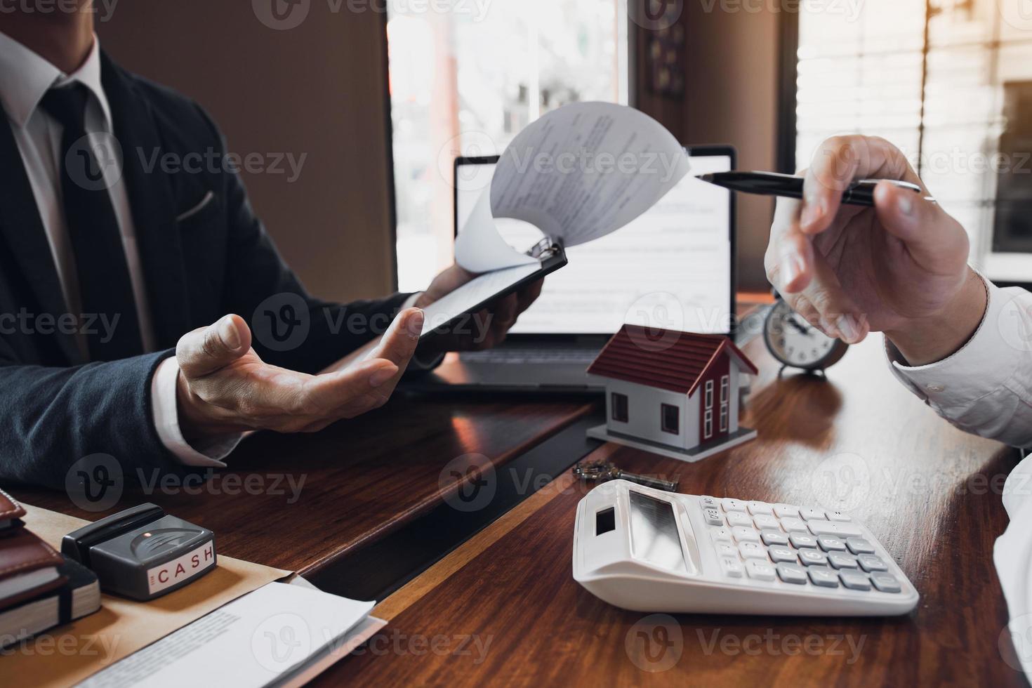 el corredor de ventas de casas de gente de negocios está usando un bolígrafo que apunta al modelo de la casa y describe los diversos componentes de la casa. foto