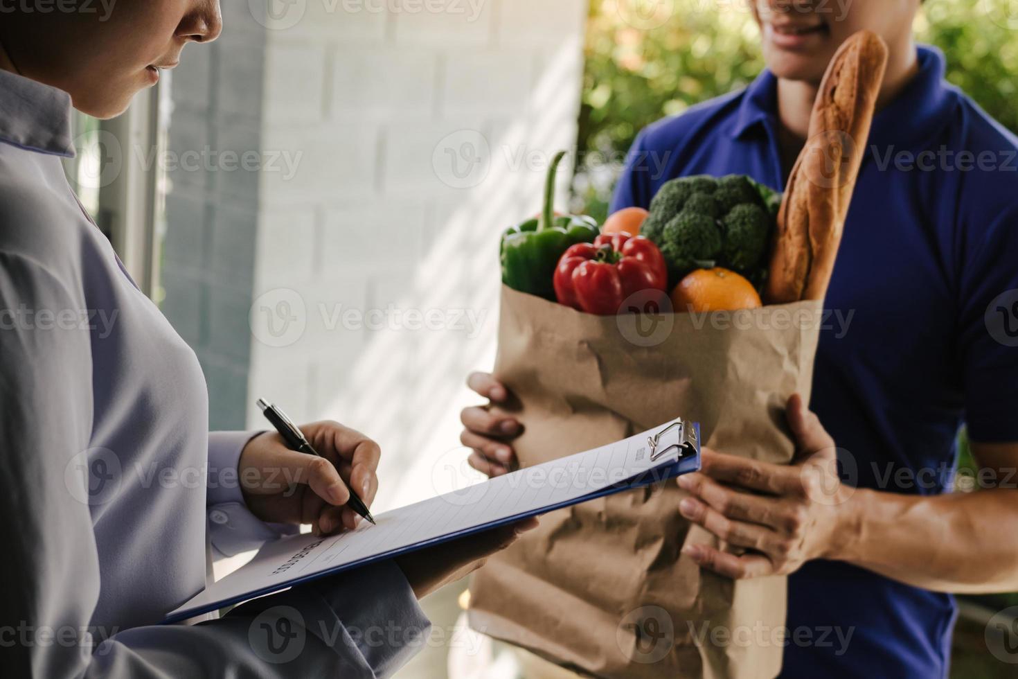 Asian woman is checking the product and signing the receipt on the order receipt through the online supermarket's home store. photo