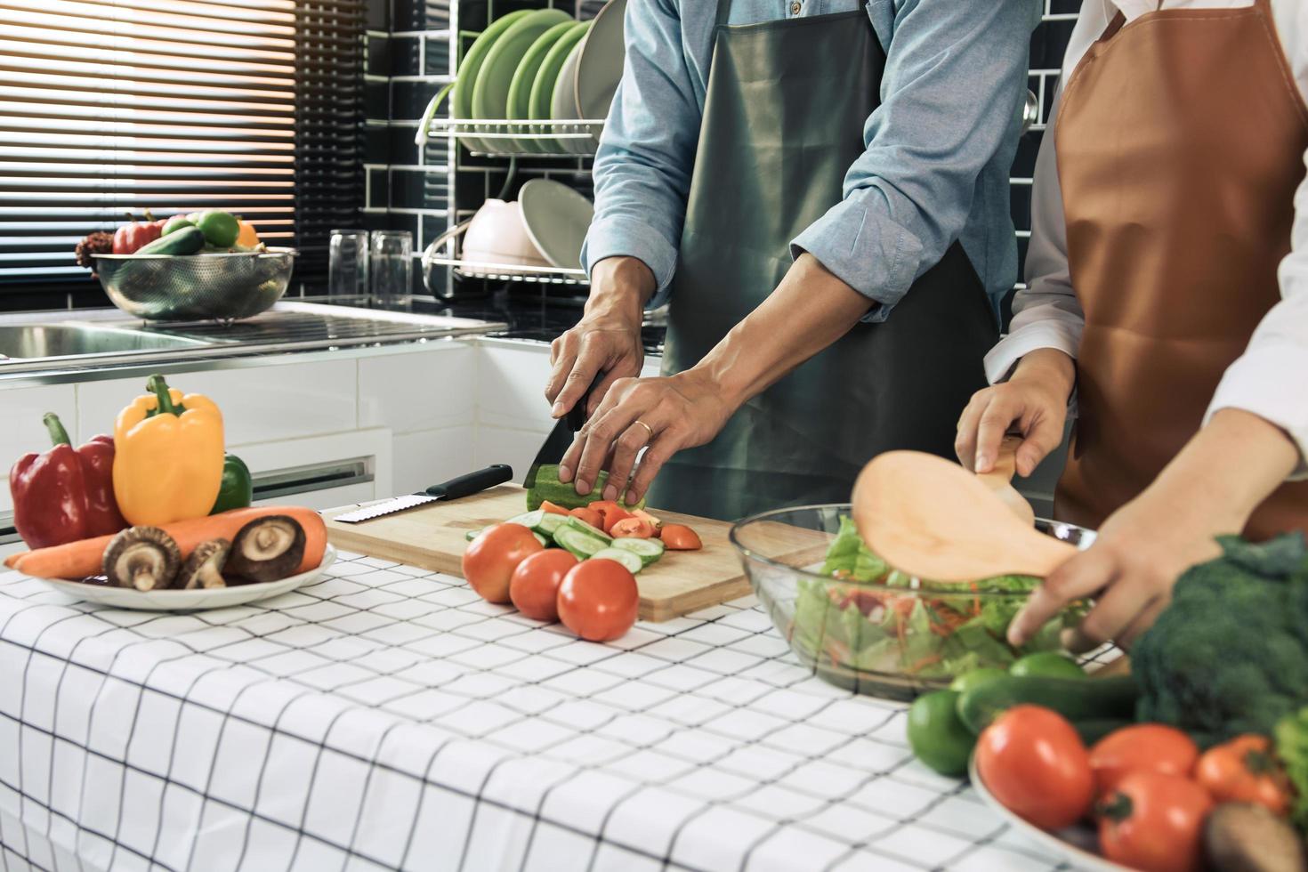 dos jóvenes parejas asiáticas se ayudan y disfrutan cocinando en la cocina. foto