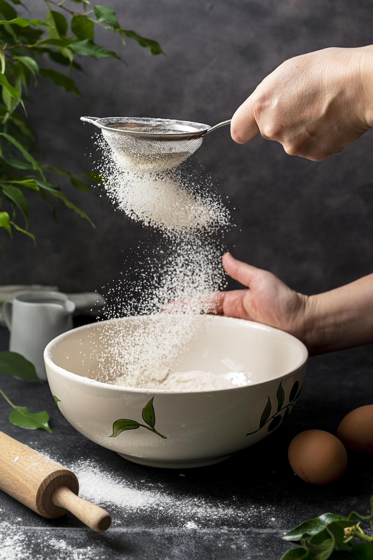 Woman's hand sifting flour through sieve. Selective focus. Baking