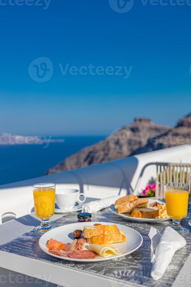 hora del desayuno en santorini en el hotel. estado de ánimo de lujo con tortilla fresca y frutas con jugo sobre la vista al mar. Fondo de vacaciones de viaje de verano de lujo. vibraciones felices y relajadas, mesa de primer plano de la mañana de pareja foto