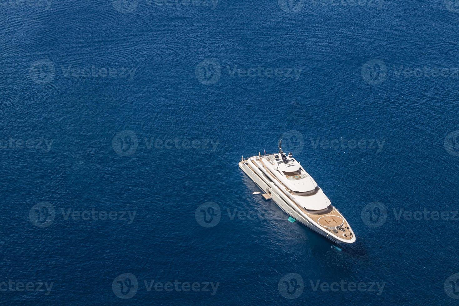 Aerial drone ultra wide photo of luxury yacht with wooden deck anchored near port. Luxury private motor yacht sailing at sea