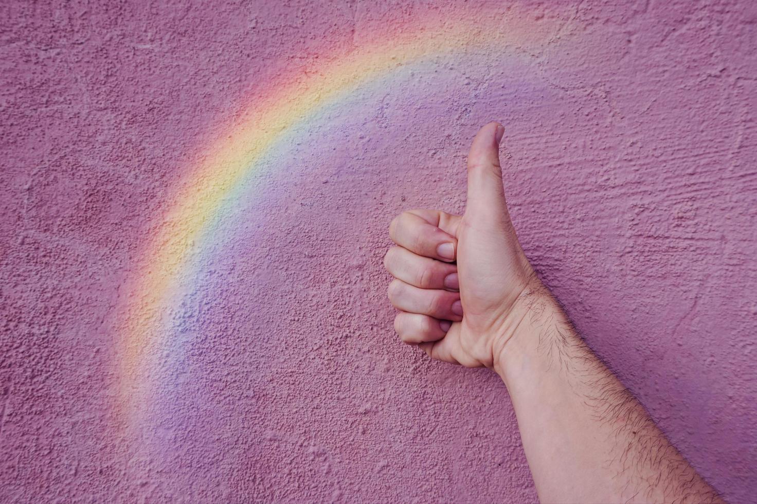 hand with a rainbow on the pink wall. lgbt symbol photo