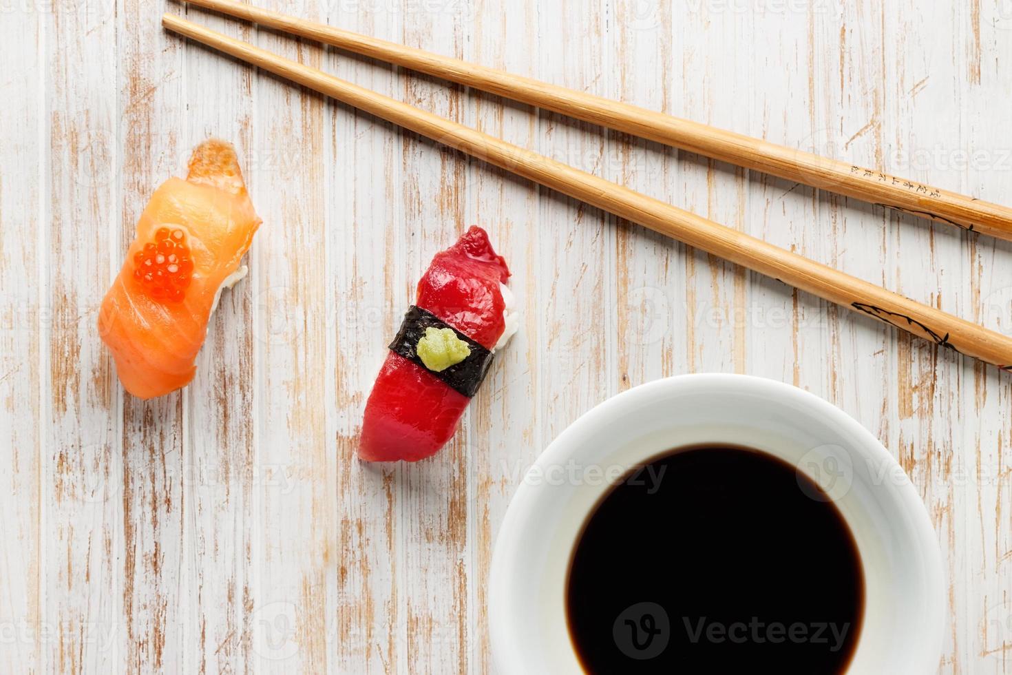 Raw fish Nigiris on old white wood with chopsticks and bowl of soy sauce. Raw fish in traditional Japanese sushi style. Horizontal image. photo