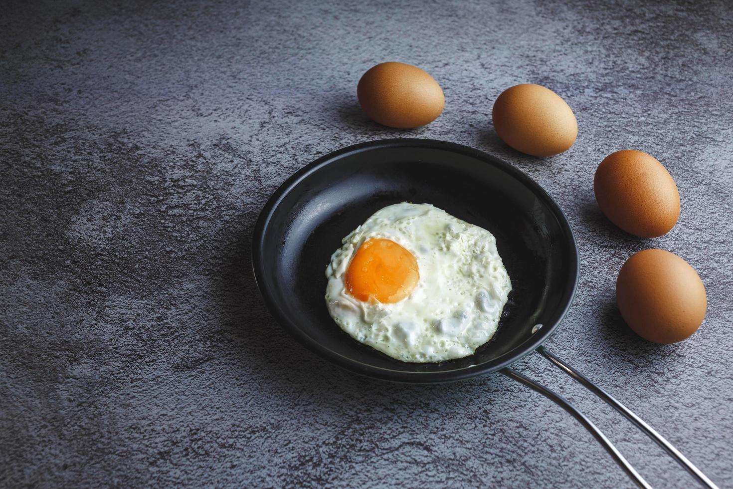 huevos fritos en una sartén y huevos frescos en la mesa foto