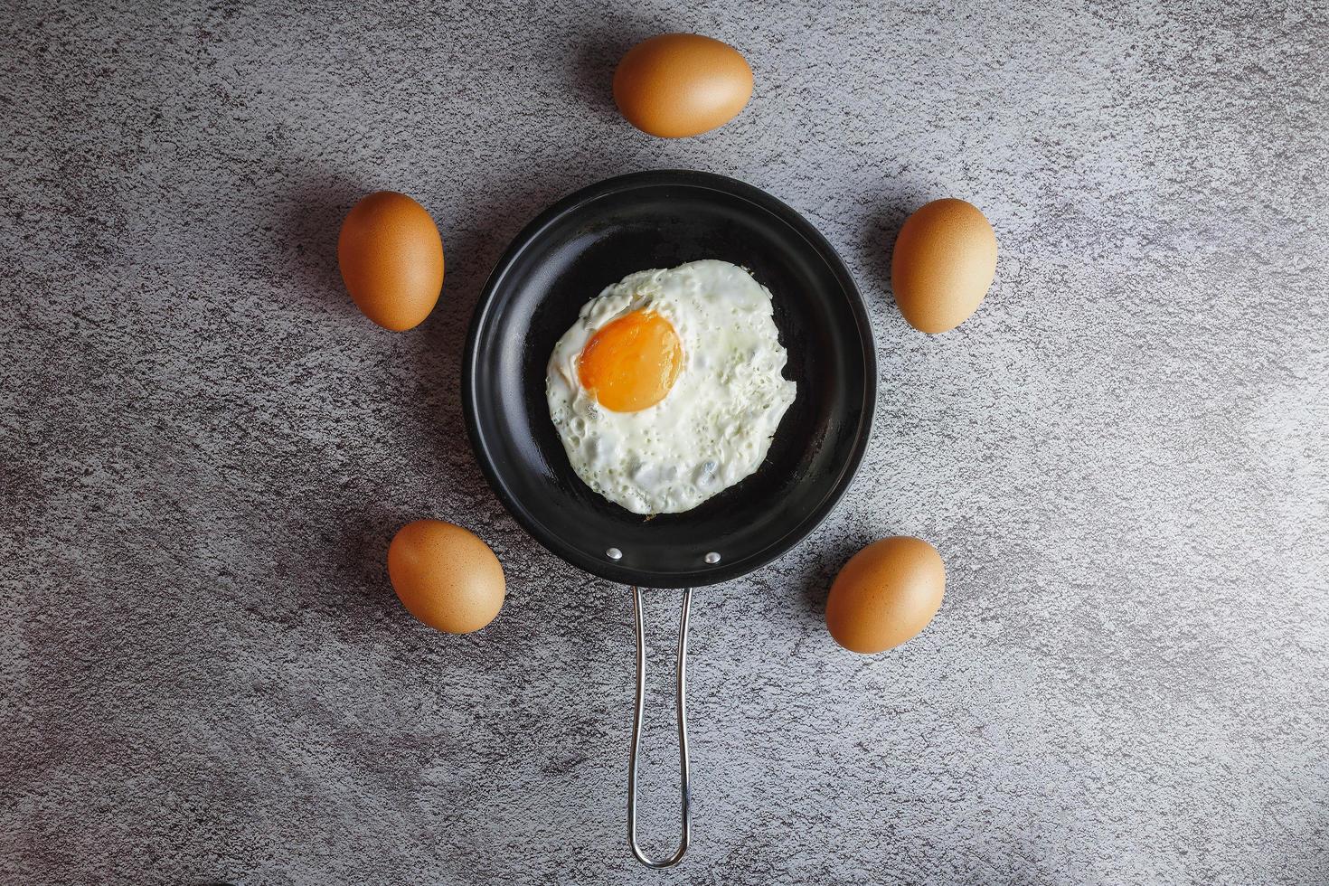 Fried eggs in a pan and fresh eggs on the table photo