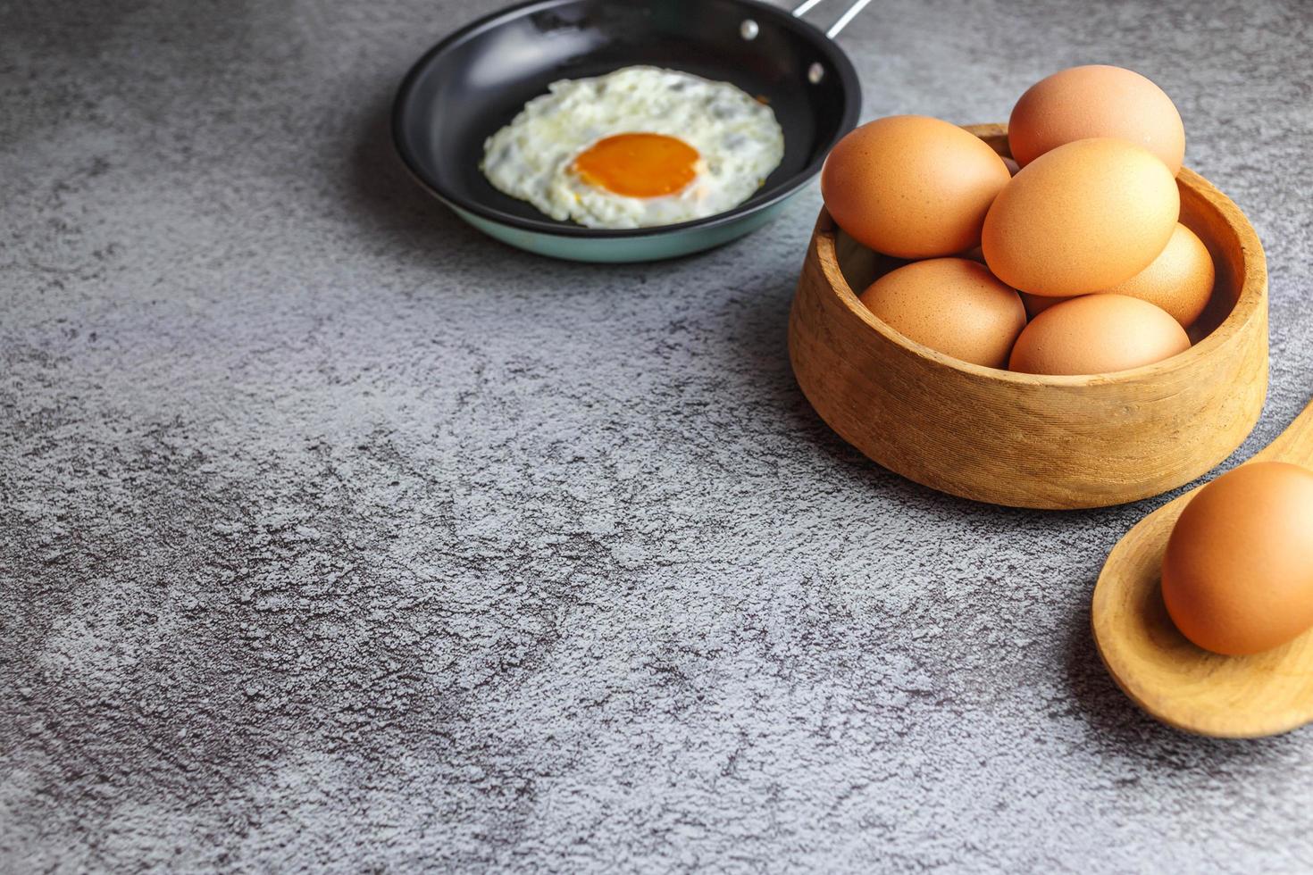 huevos fritos en una sartén y huevos frescos en la mesa foto